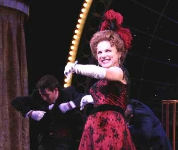 Tovah Feldshuh as Dolly Gallagher Levi, with Nigel Dancing behind her as one of the waiters
