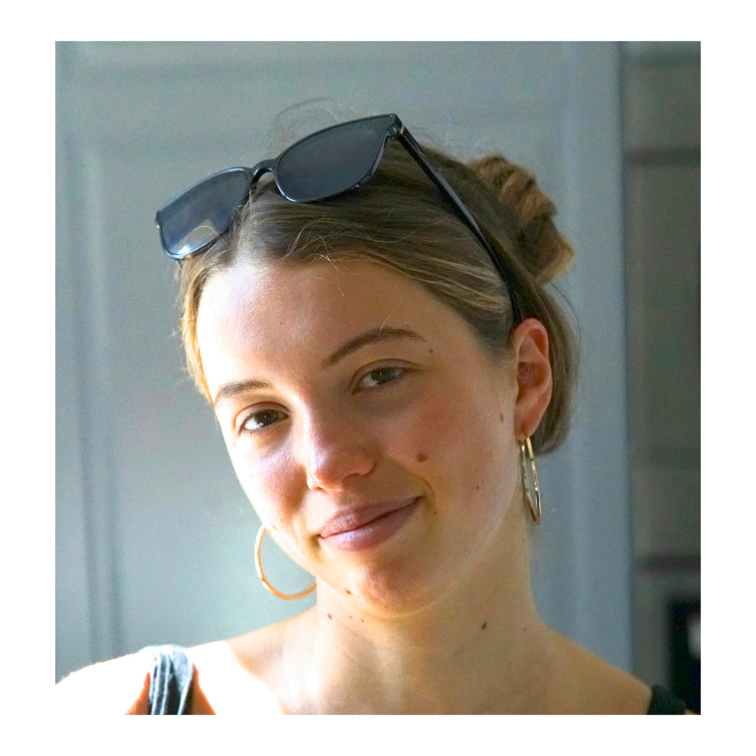 A young woman with a topknot hairstyle, sunglasses on her head