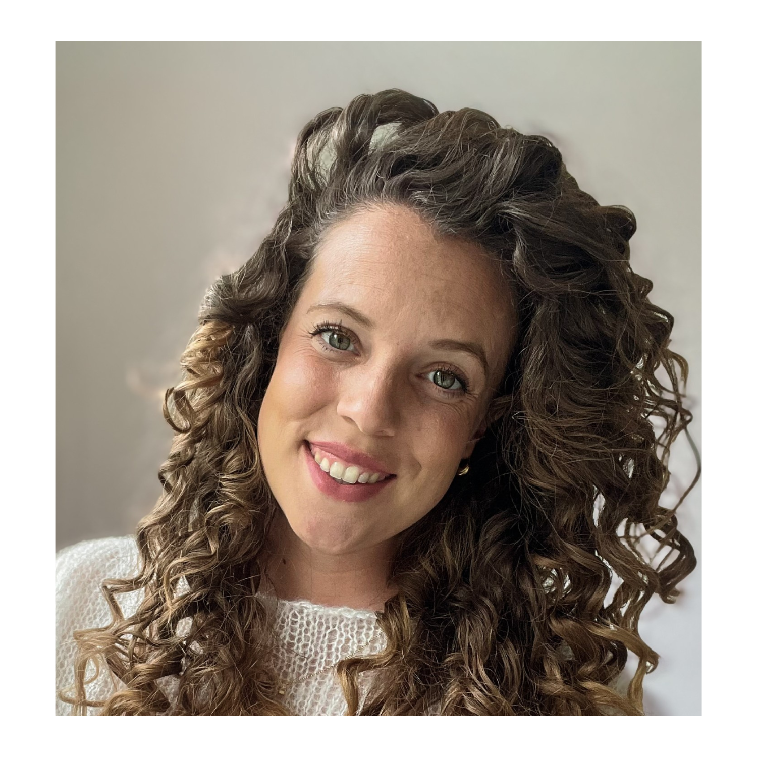 A young woman smiling with curly hair