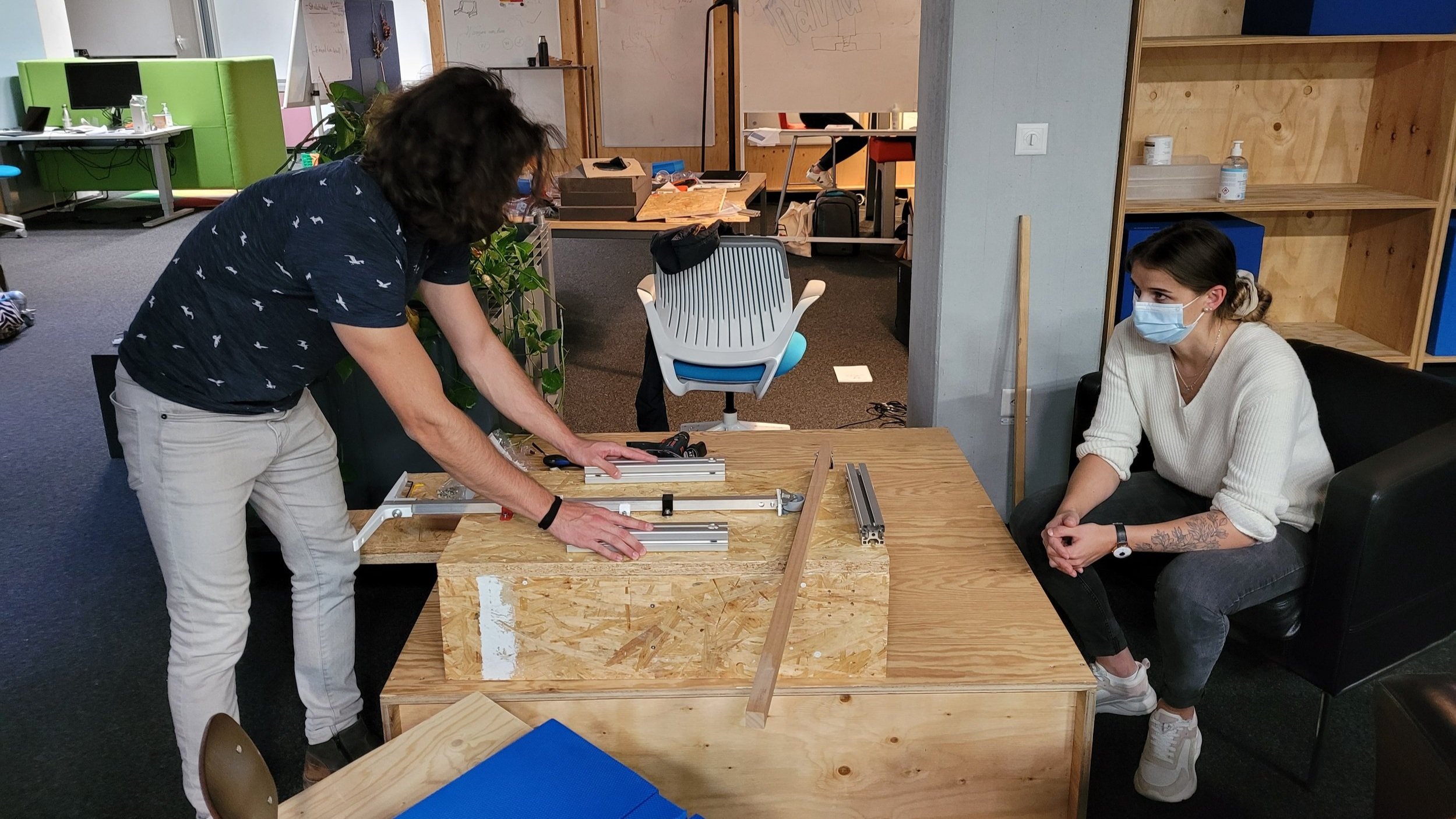 Two participants are working on the prototype, that looks like a wooden box with a sliding part fixed in the middle.