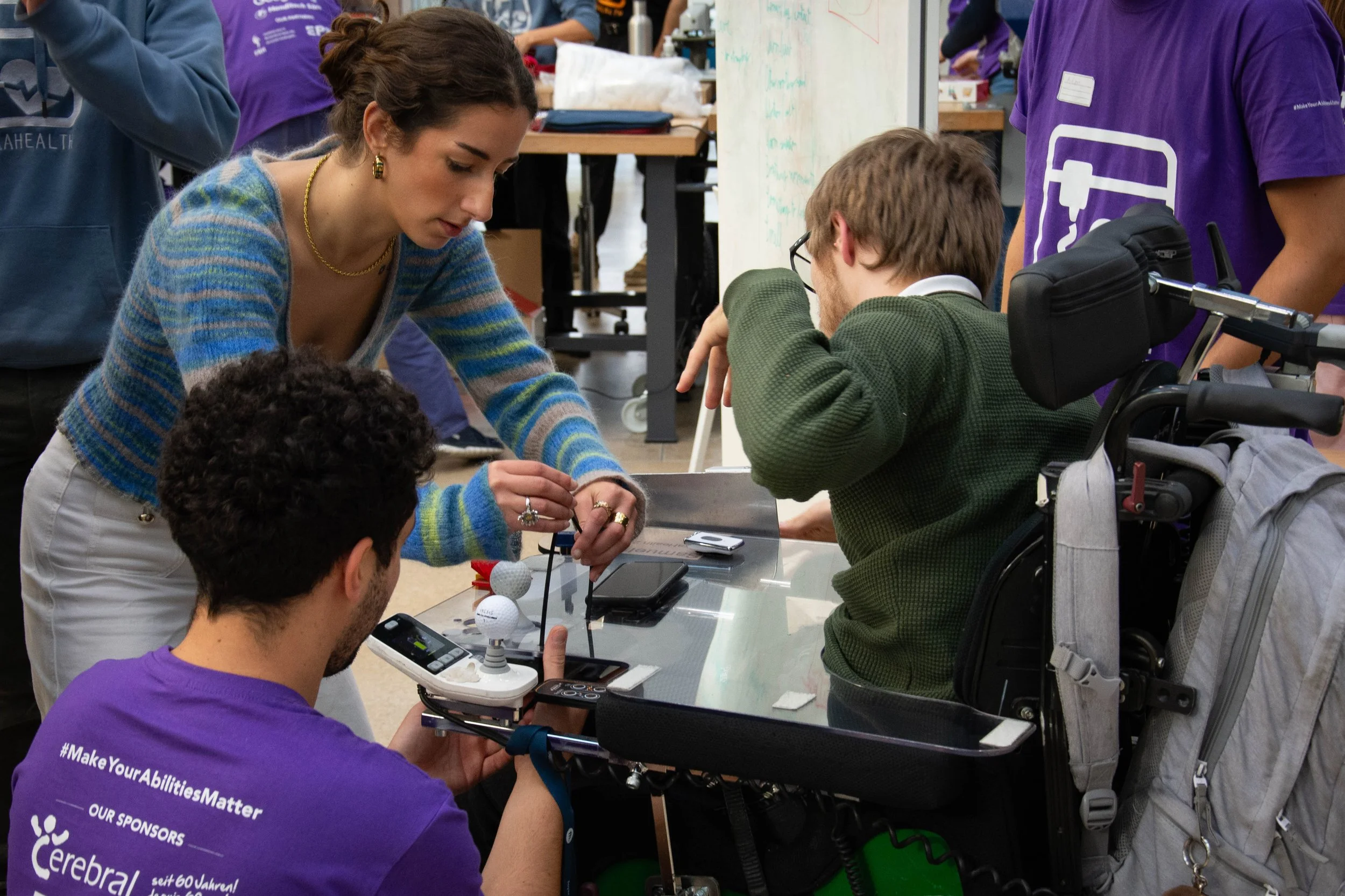 Three people working on a prototype attached to a wheelchair.