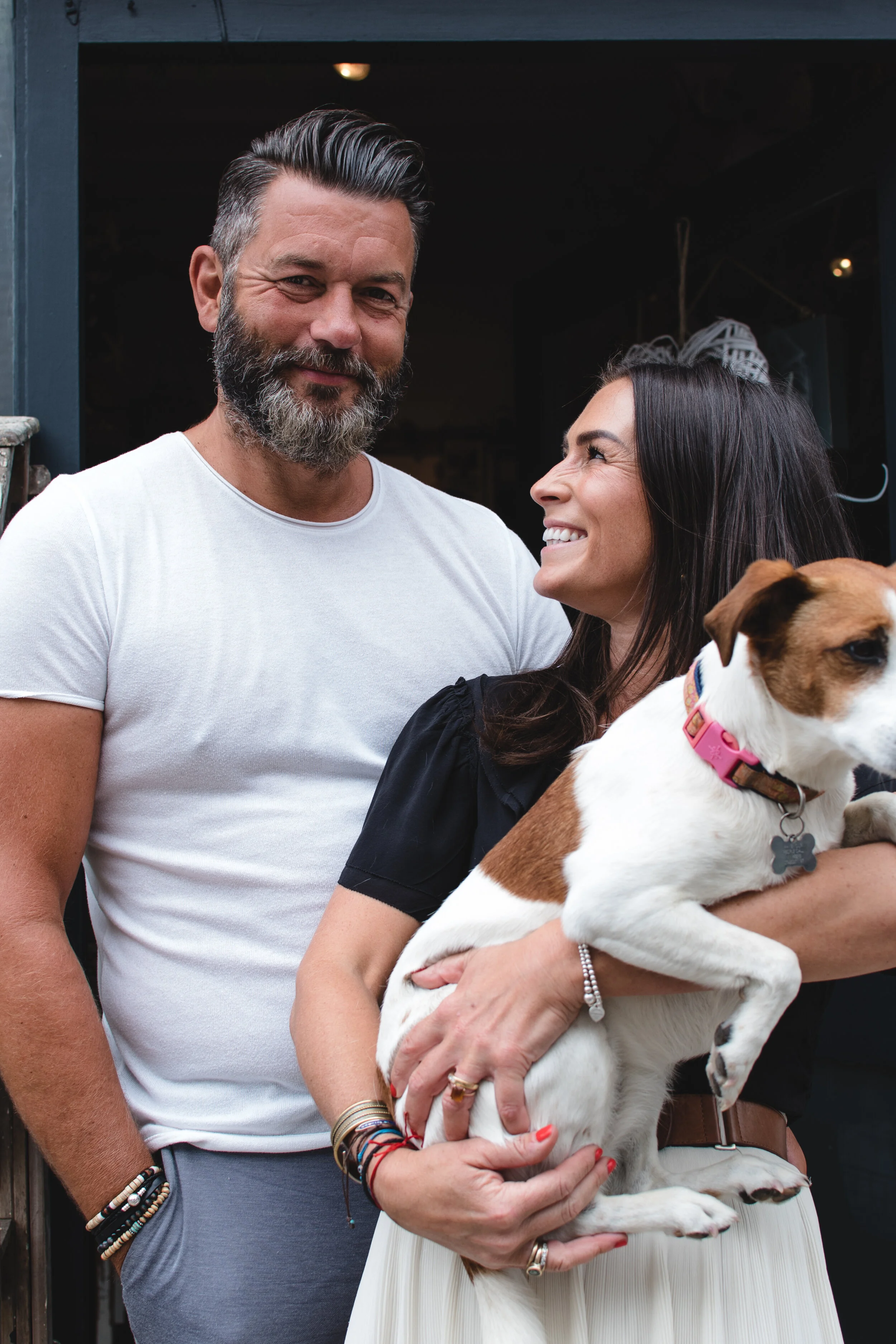 Man and woman smiling, holding a small dog
