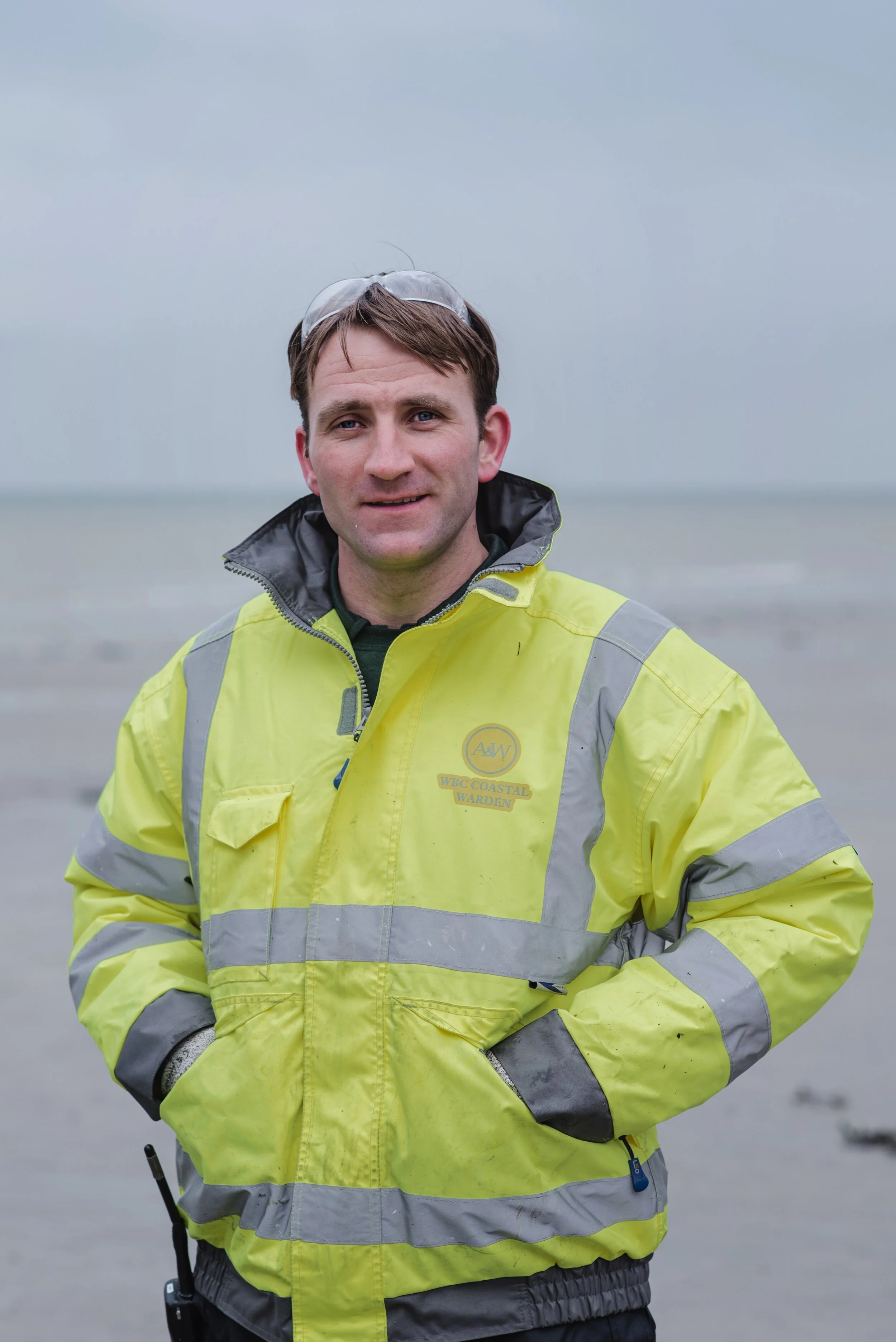 Person in high-visibility jacket standing on a beach