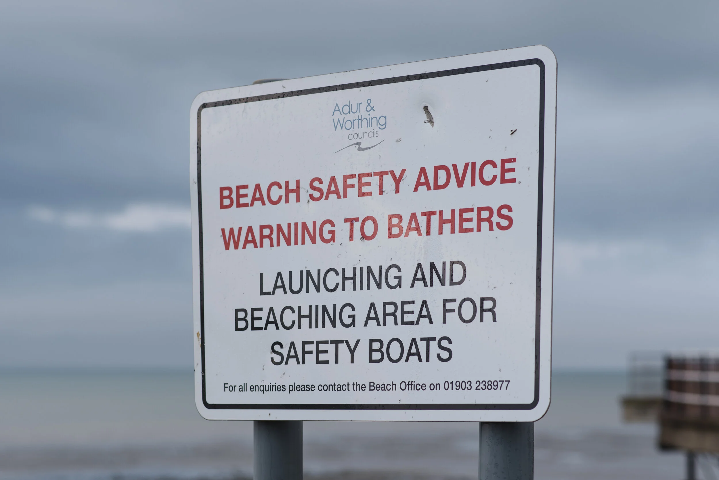 Beach safety sign warning bathers about a launching and beaching area for safety boats. It includes contact information for the beach office.