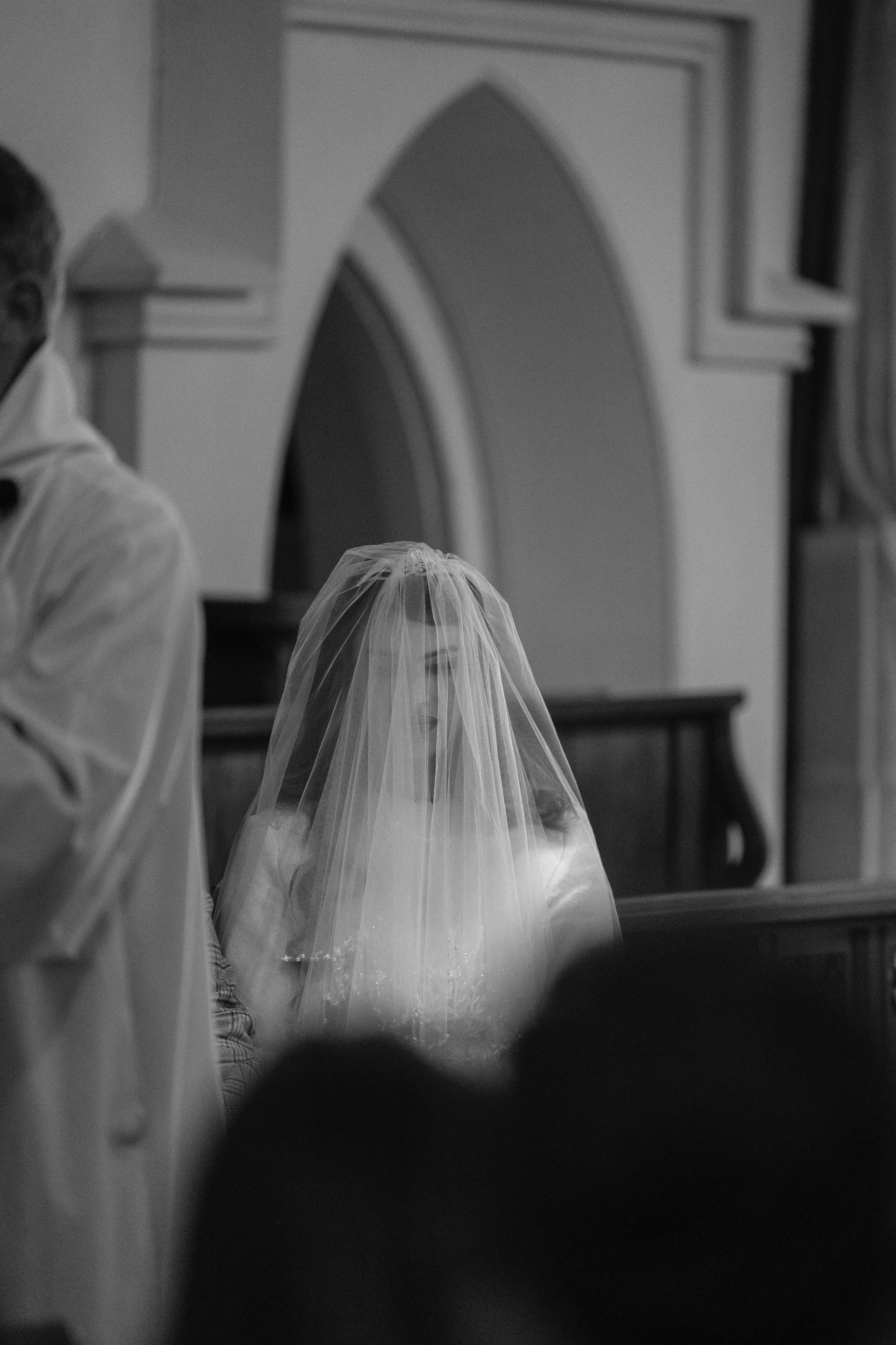 black and white image of a bride wearing a veil in a church