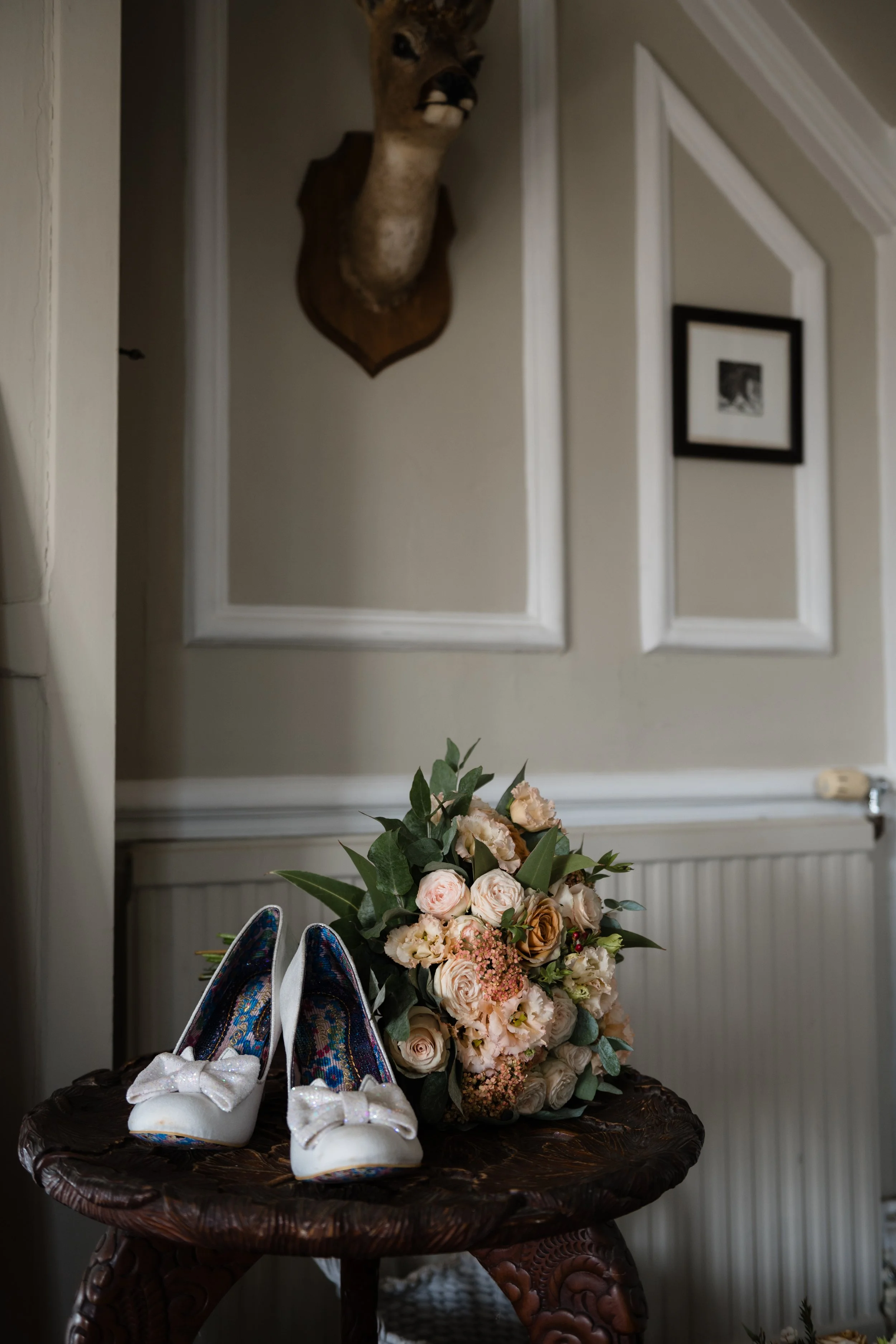 Wedding shoes and a bridal bouquet of flowers in dusky peaches and soft browns in a country cottage