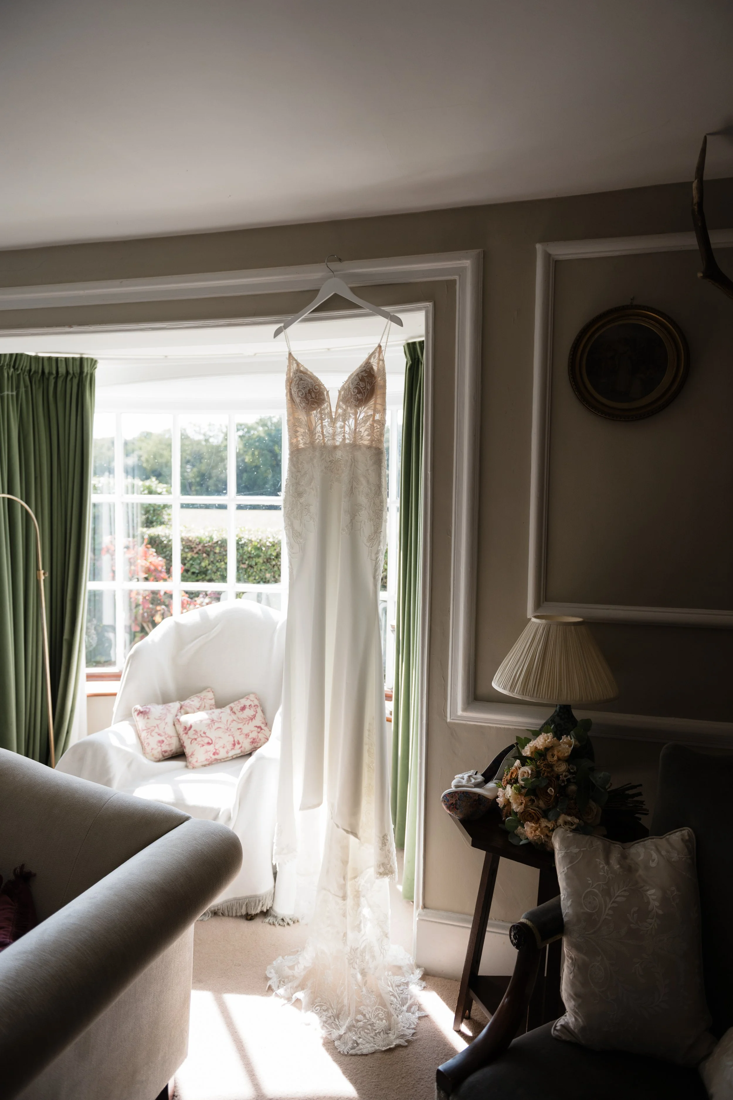 Backlit wedding gown in a bay window of a country cottage