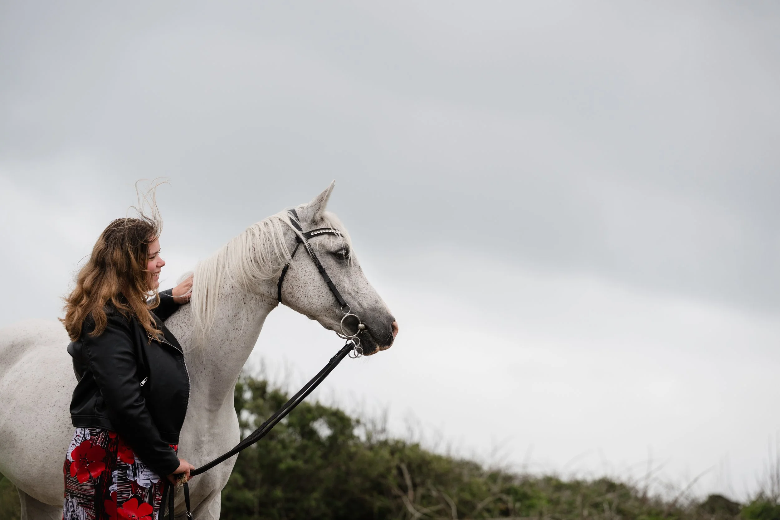 woman and horse on a windswept beach