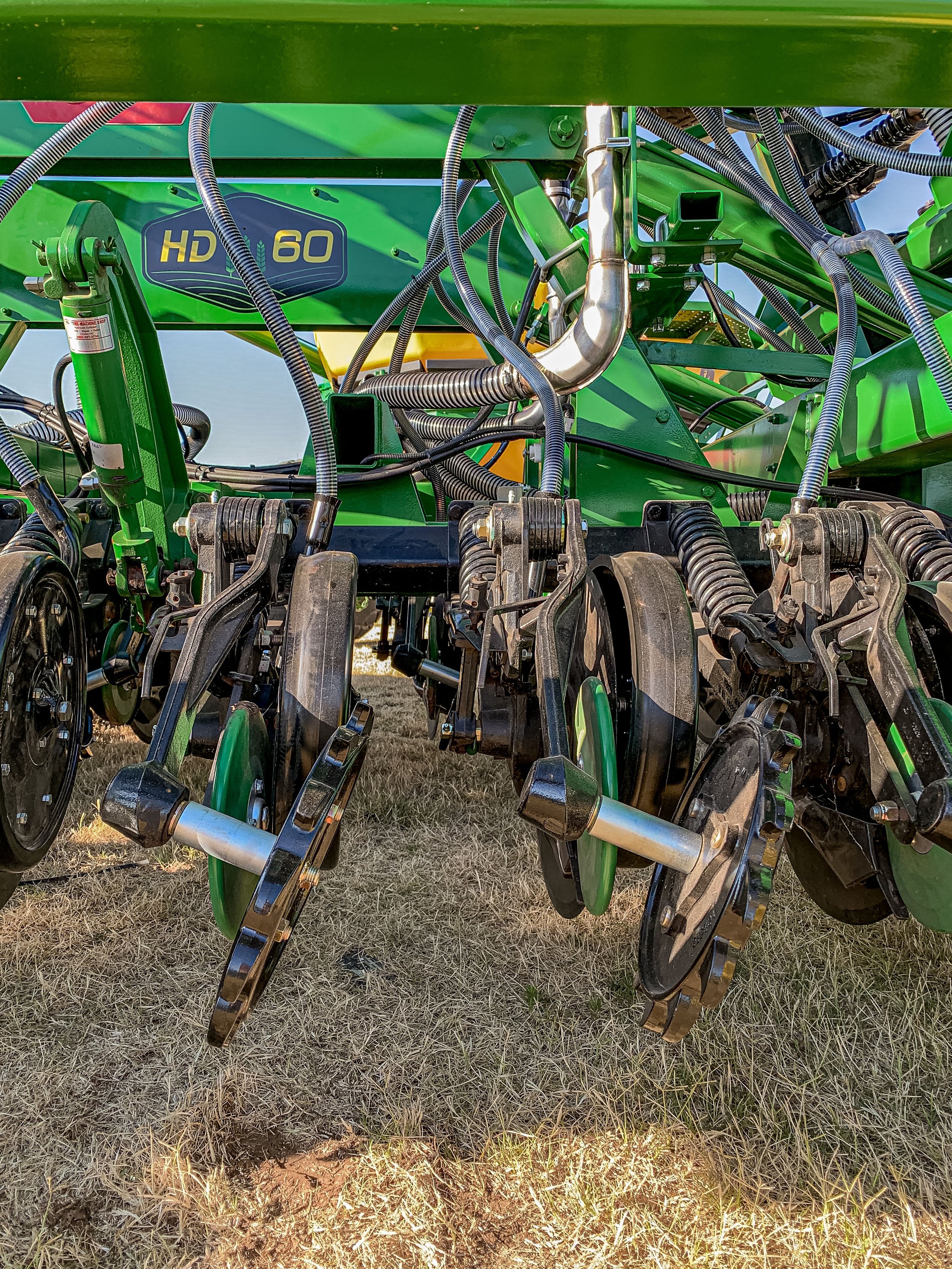 Close-up of green agricultural machinery with multiple black and green disks and hydraulic parts.