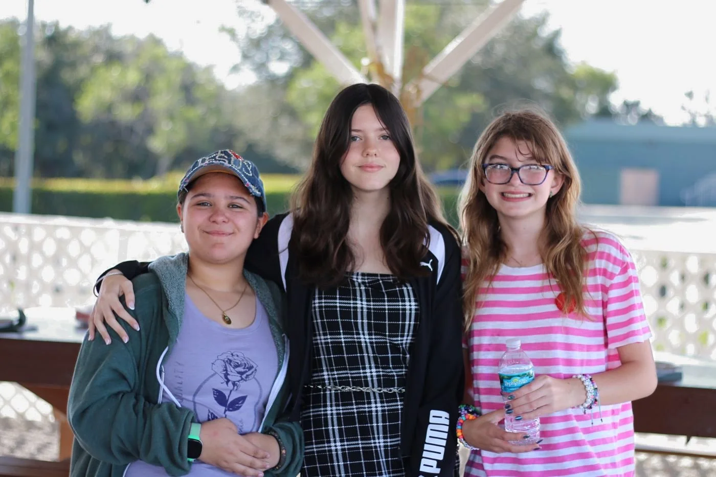 Three students standing together and smiling at the Fall Festival at Educational Pathways Academy, enjoying the school’s community event