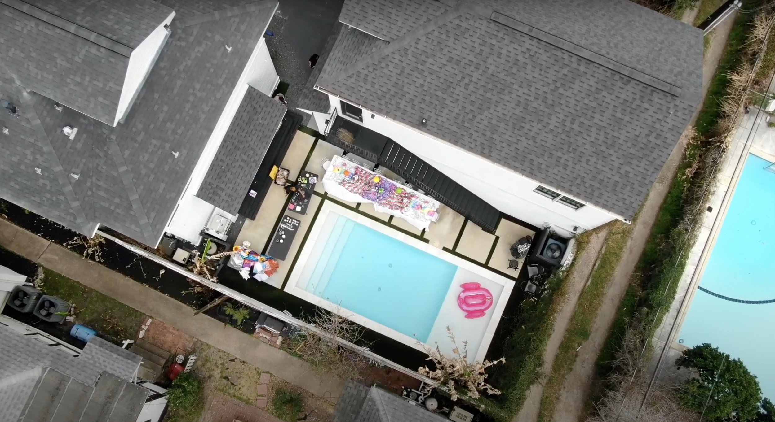 Aerial view of a backyard with a swimming pool, a painted mural on the wall, and various outdoor furniture and decorations.