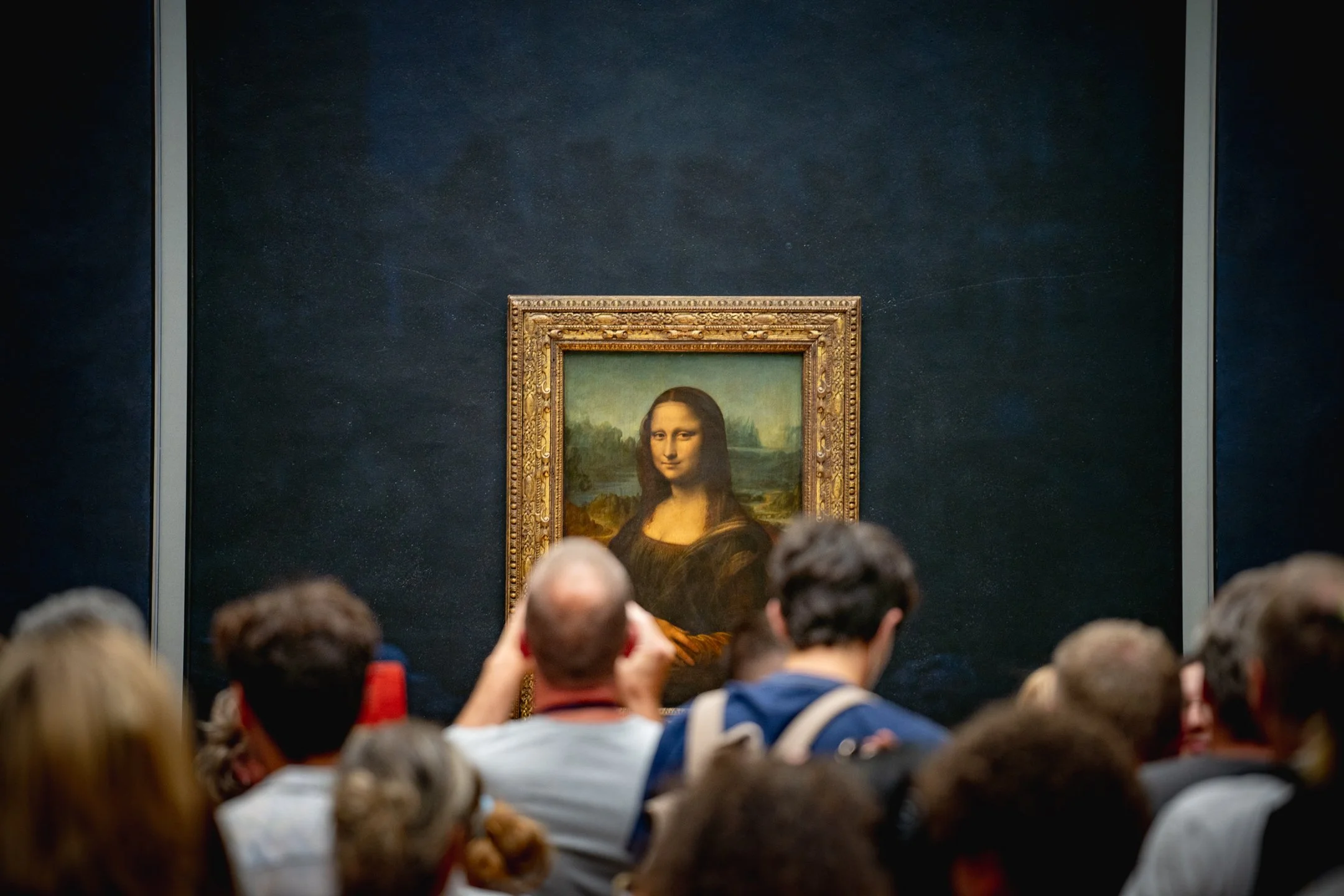 People viewing the Mona Lisa painting at the Louvre Museum.