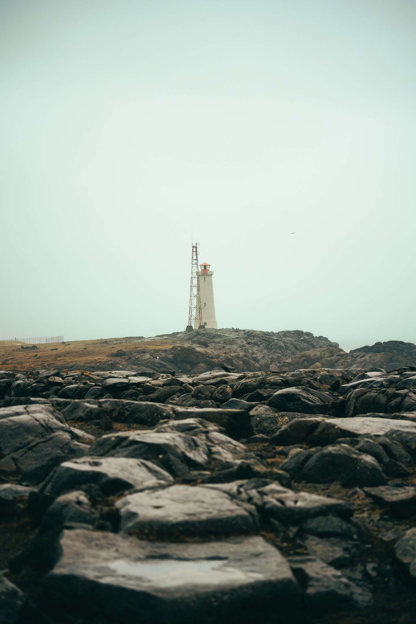 A lighthouse on a rocky shore under an overcast sky.