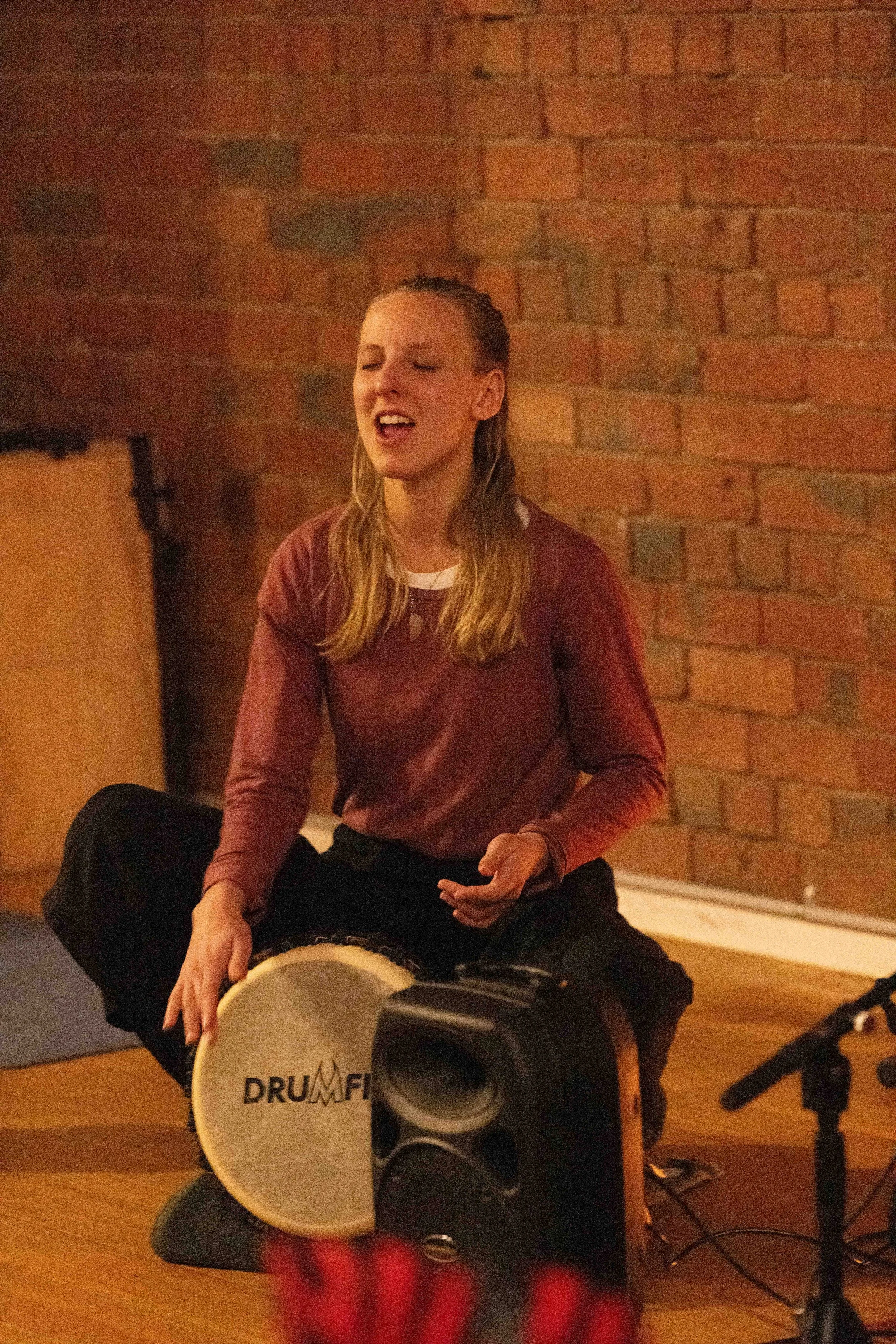 Molly Rose leading kirtan chanting and devotional mantra practice in a group setting.