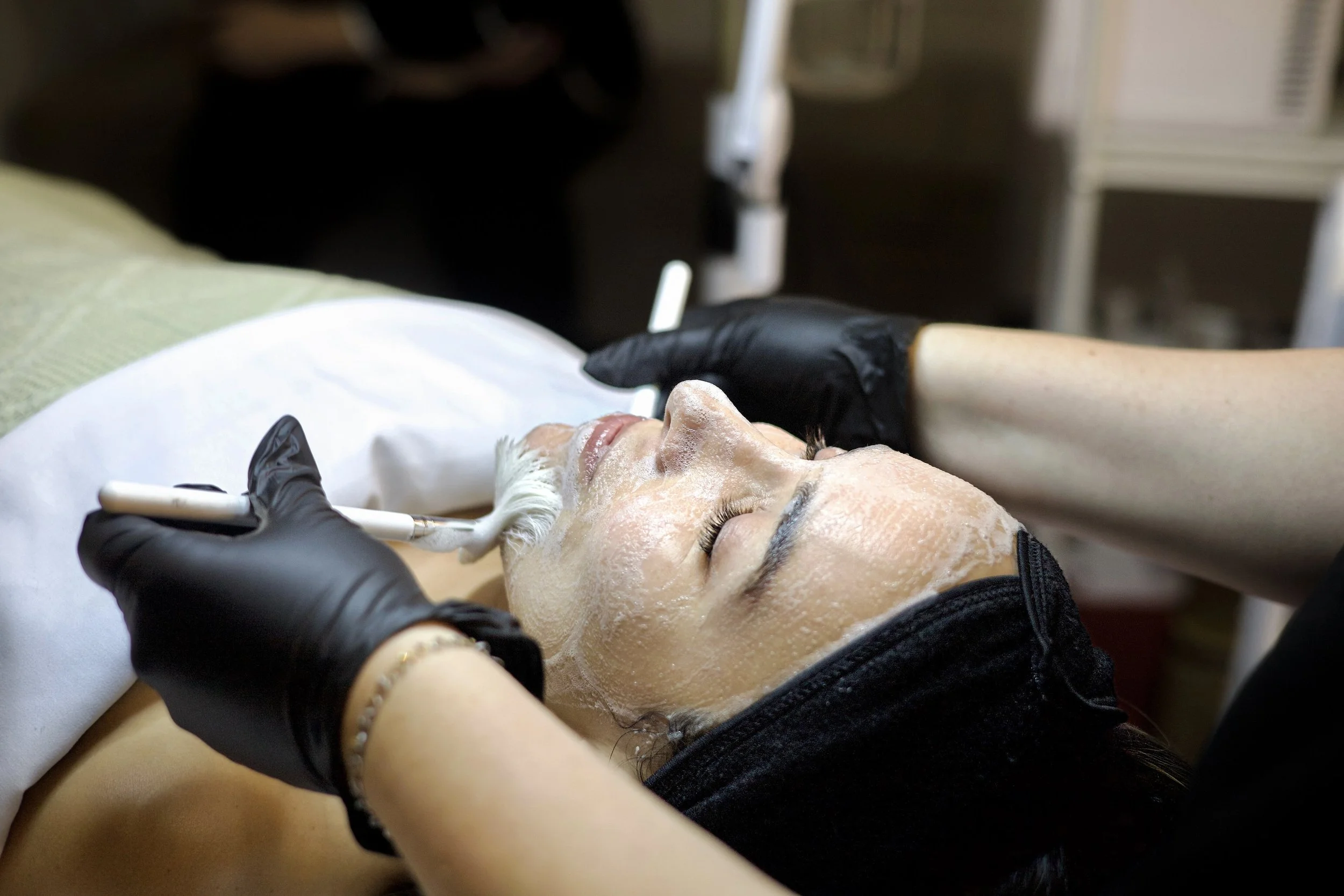 Brushes applying cleanser during custom facial