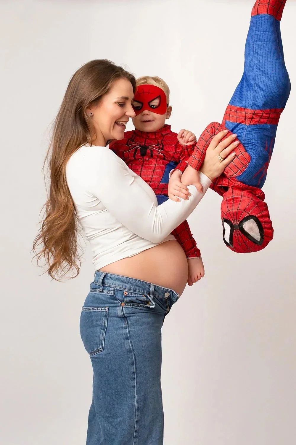 pregnant mum and two toddlers dressed as superheroes having fun during their family photoshoot in Cheltenham