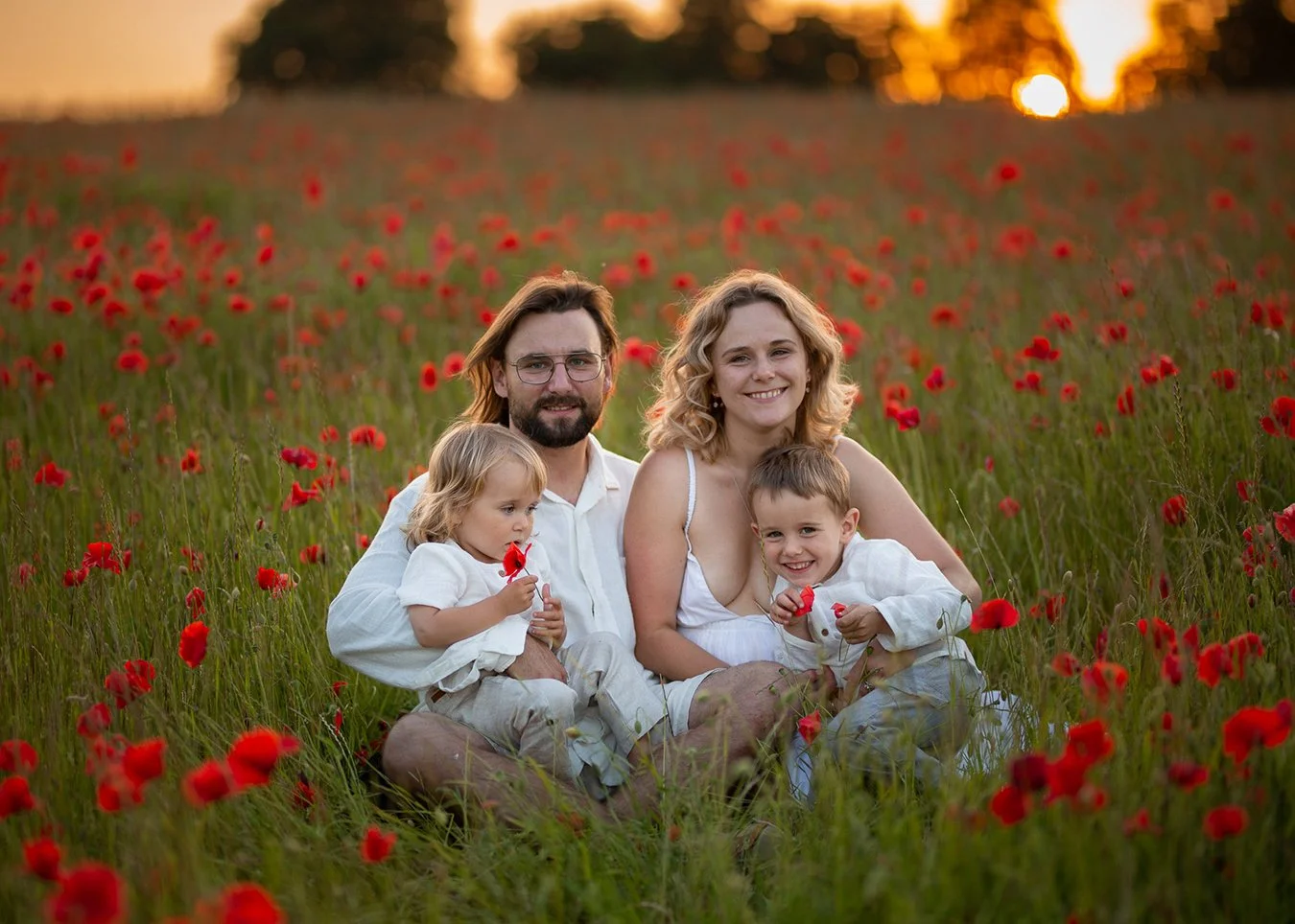 a family with two little boys smiling during a fun family photoshoot in the Cotswolds