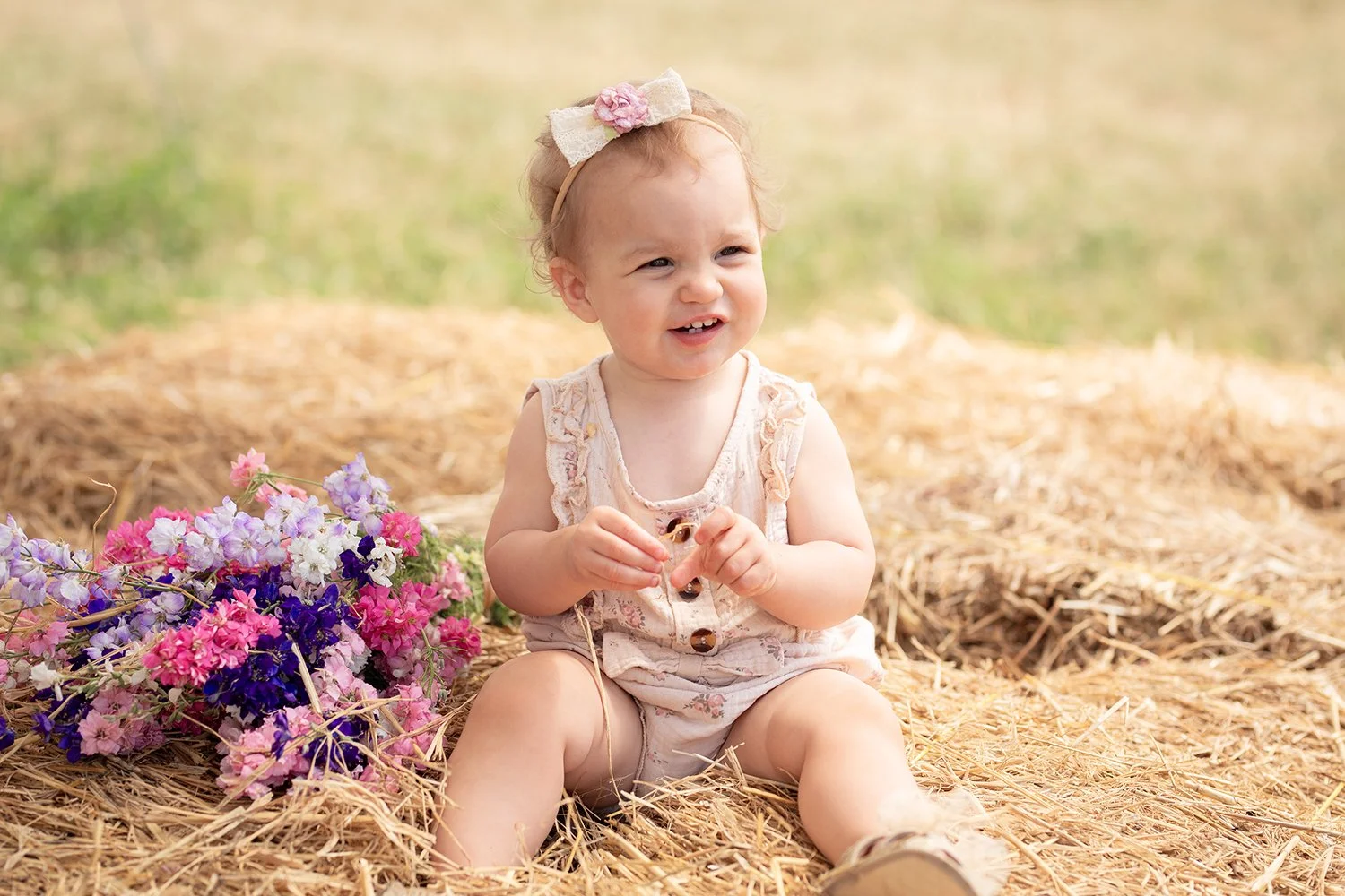 baby sitting with a bouquet during a mini session in confetti field near Worcester