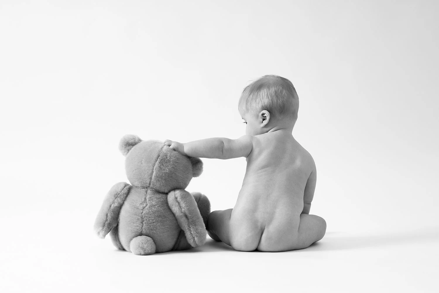 black and white photo of a baby and teddy bear taken during a sitter session in Cheltenham Gloucestershire