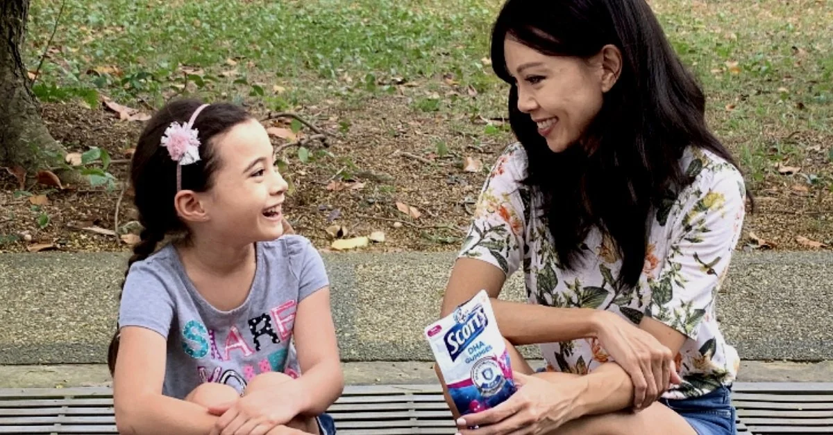 A mother smiling to her child holding a packet of Scotts DNA Gummies