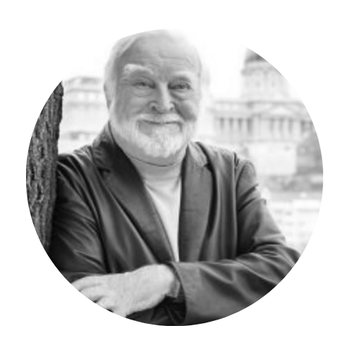 Man in a suit smiling near a tree