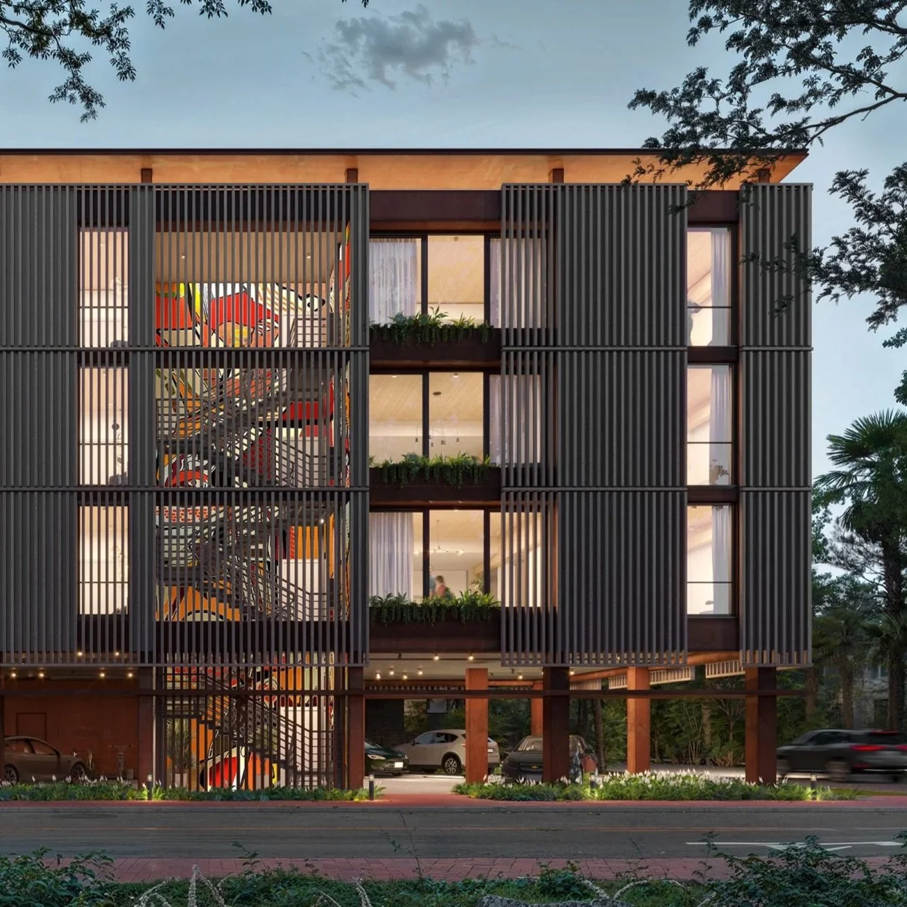 Modern multi-story building with an external artistic staircase and vertical wooden slats, illuminated windows, and greenery on balconies, with cars parked underneath and trees nearby, during dusk.