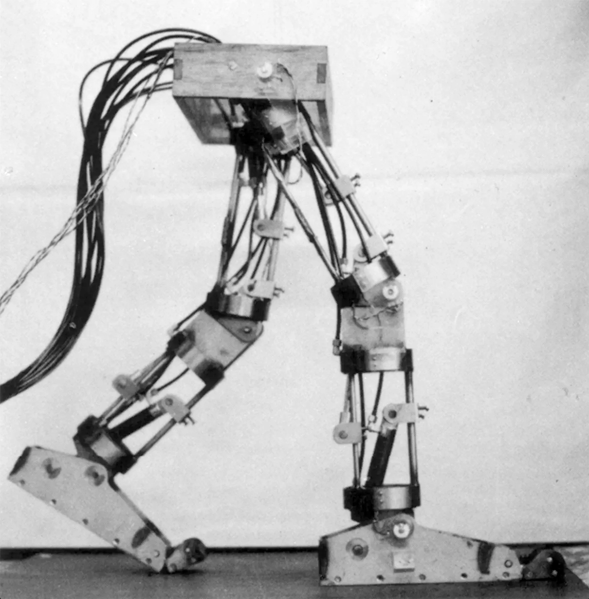 Black and white photo of a mechanical robotic leg with multiple joints and wires.