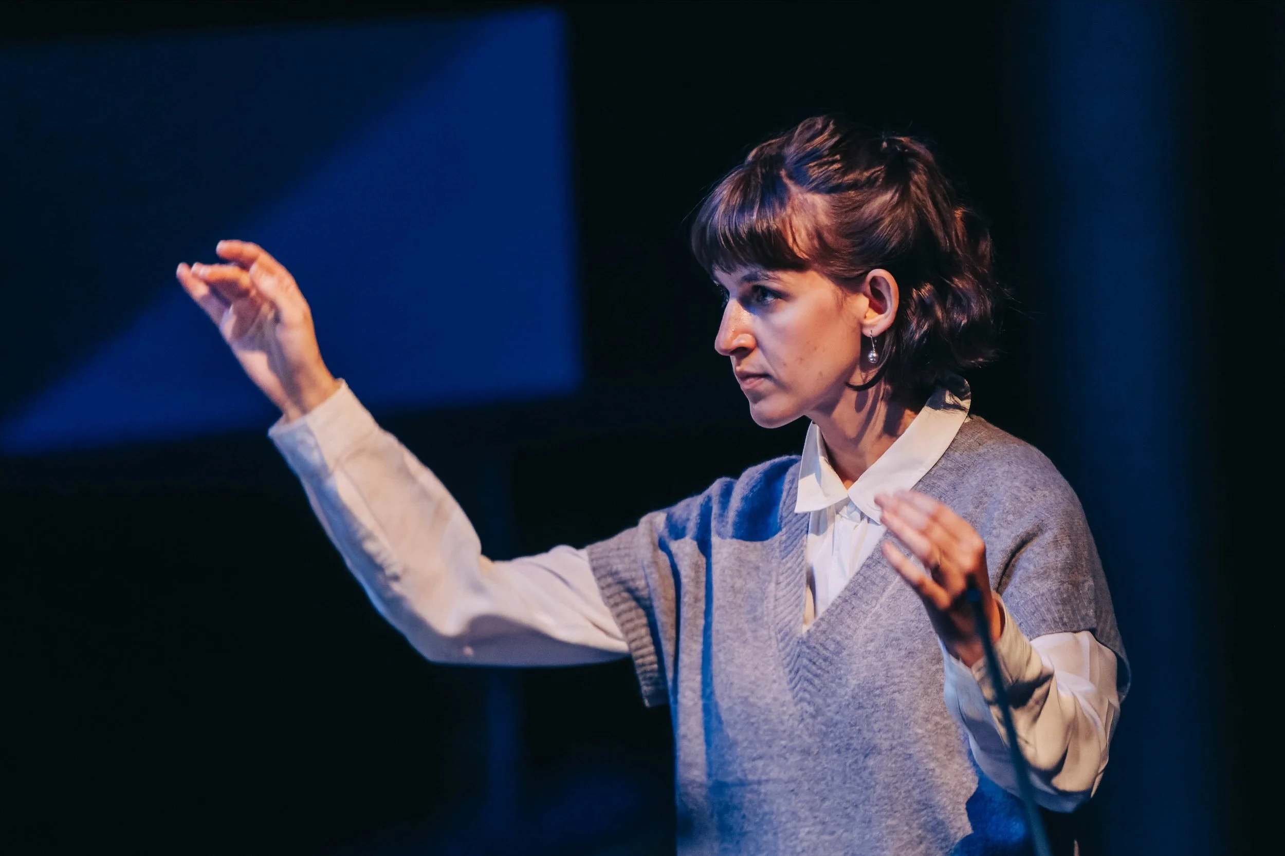 Conductor Gabrielle Goudreault right hand raised ready to cue the choir.