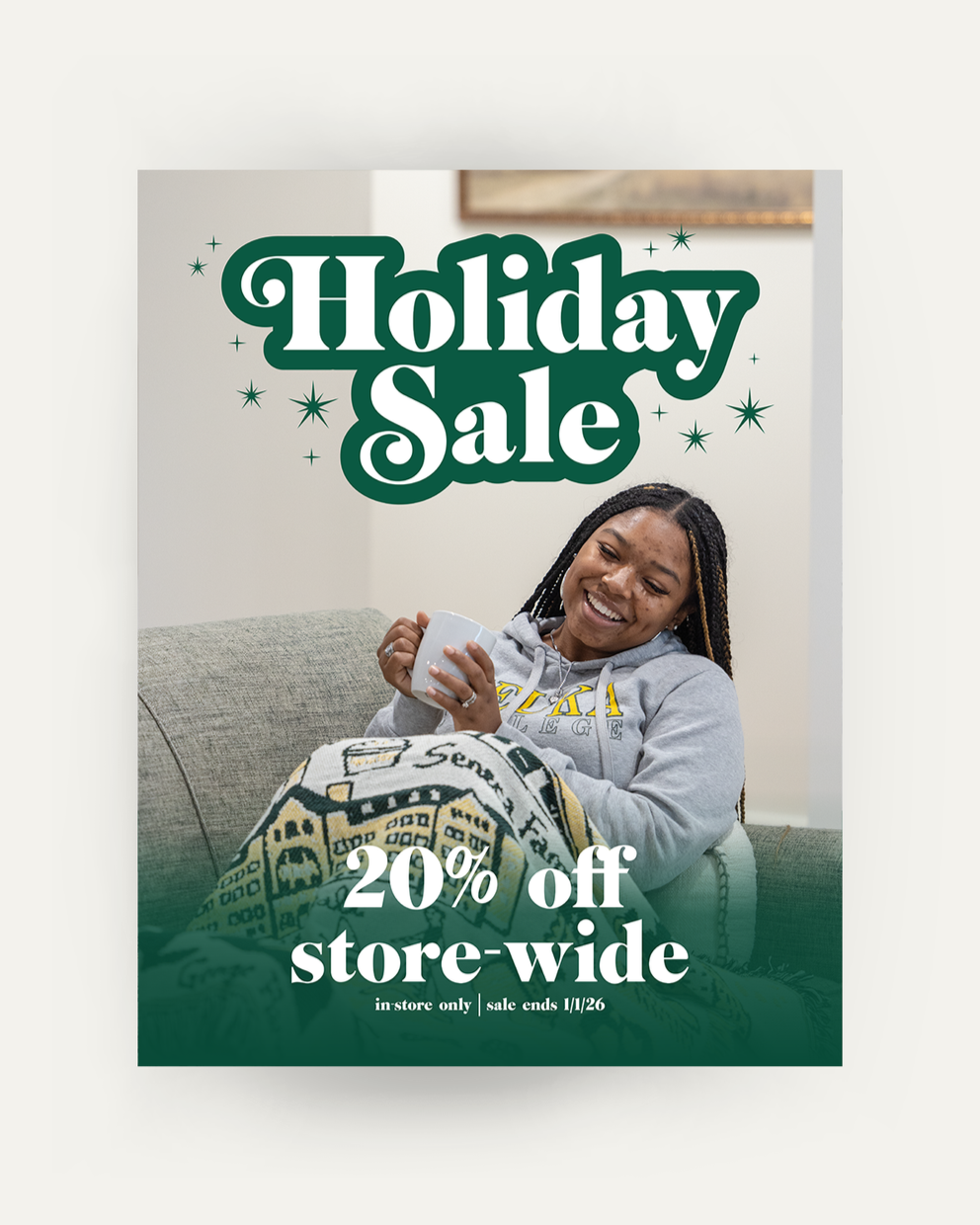 Poster advertising the holiday sale of 20% off store-wide, in-store only, sale ends January 1st 2026. It shows a girl dressed in a Keuka College sweatshirt under a Keuka College blanket.