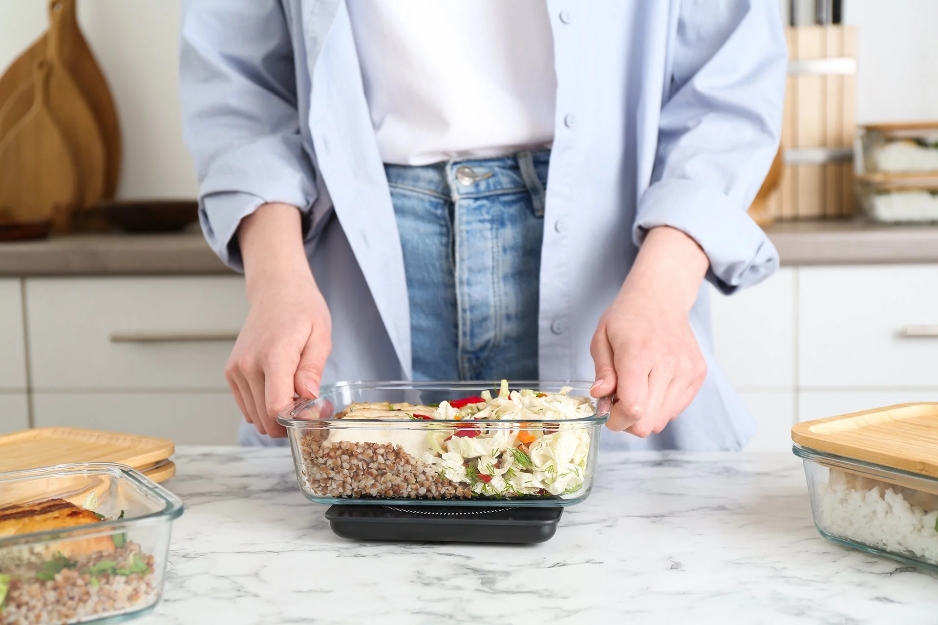 A person prepares a balanced meal in a glass food container, illustrating meal planning and preparation for a loved one.