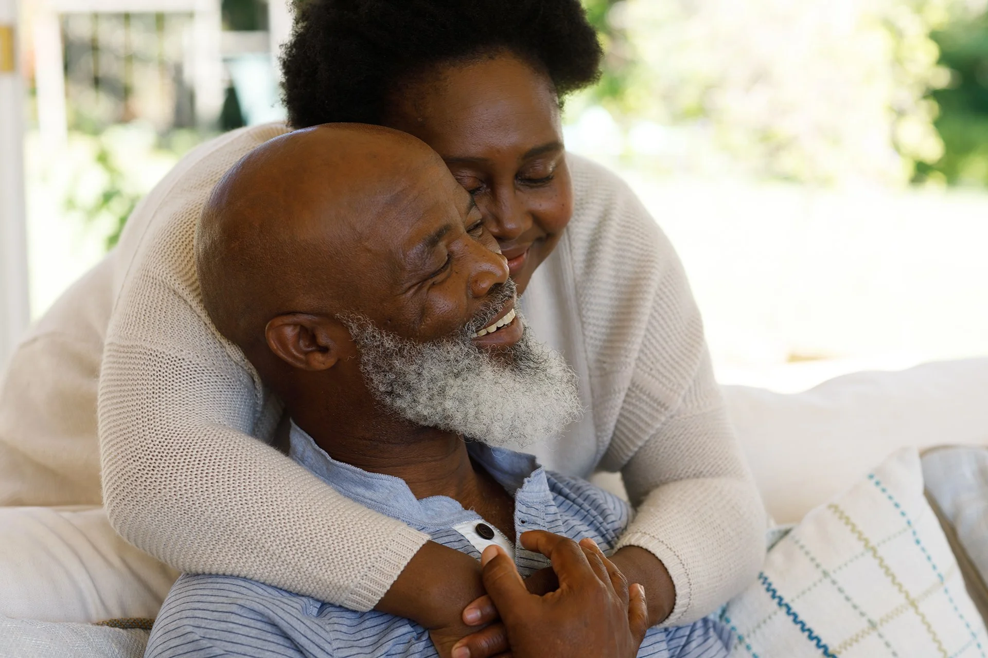 An adult daughter hugs her smiling father while spending quality time together at home.