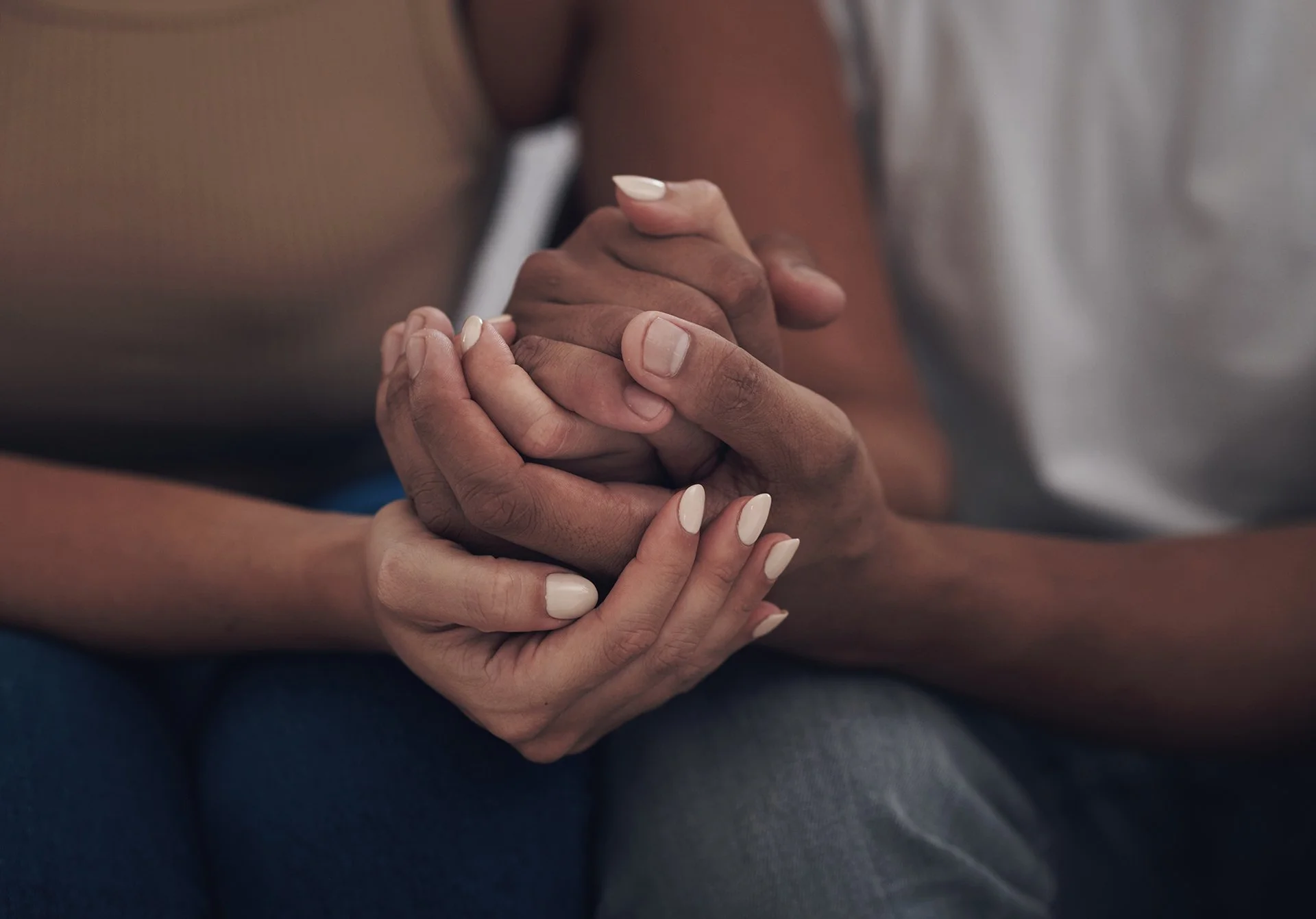 Two people gently holding hands as a reminder that true support can empower growth rather than remove every challenge.