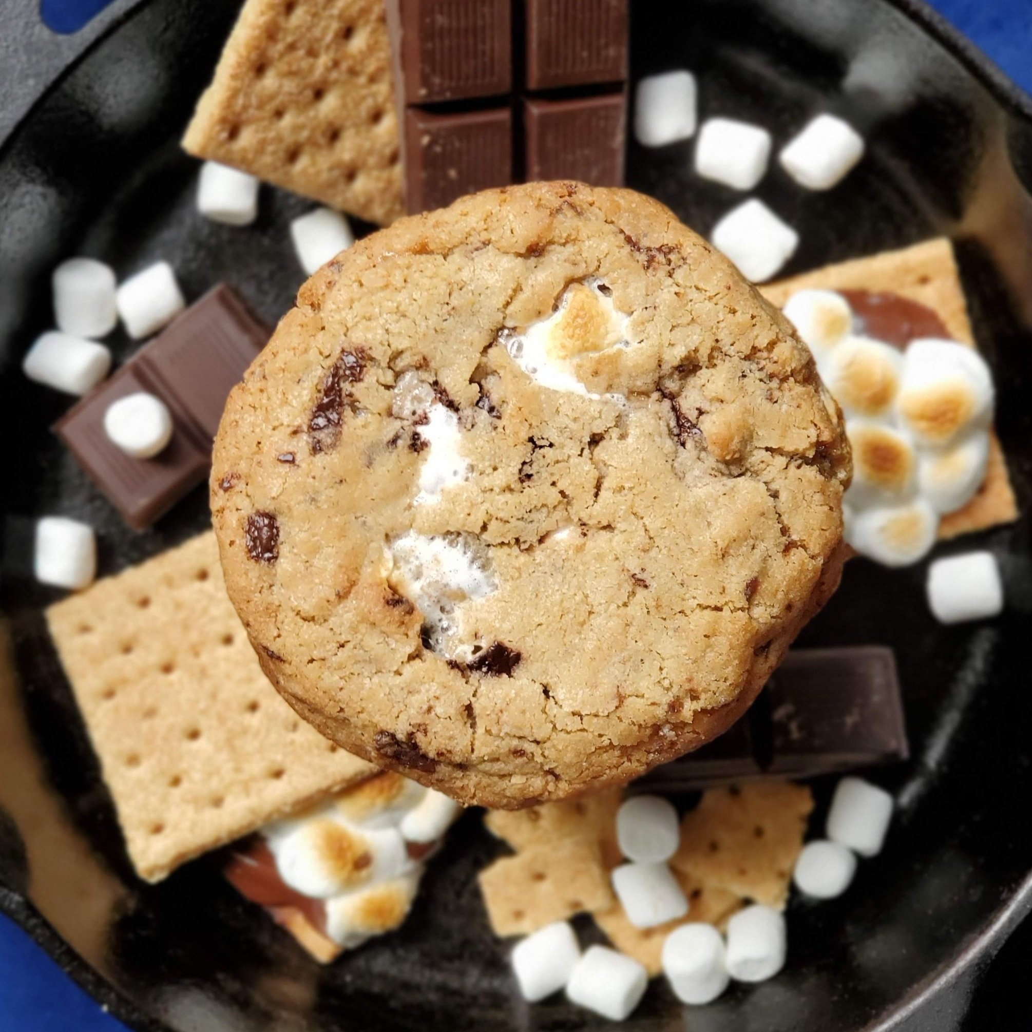 s'mores cookie with graham crackers, marshmallows, and chocolate on cast iron background