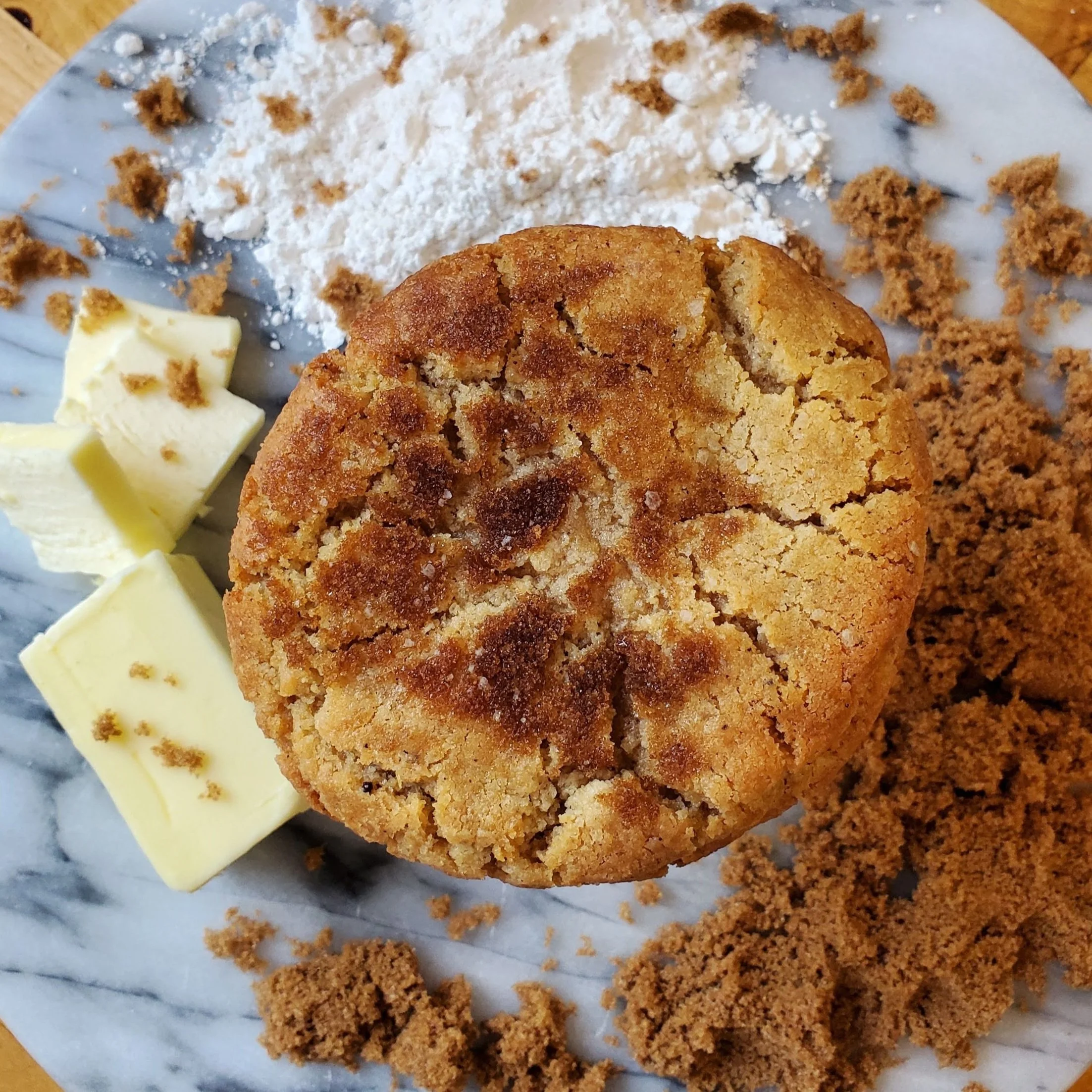 sugar coated cookie with flour, sugar, and butter on a marble background