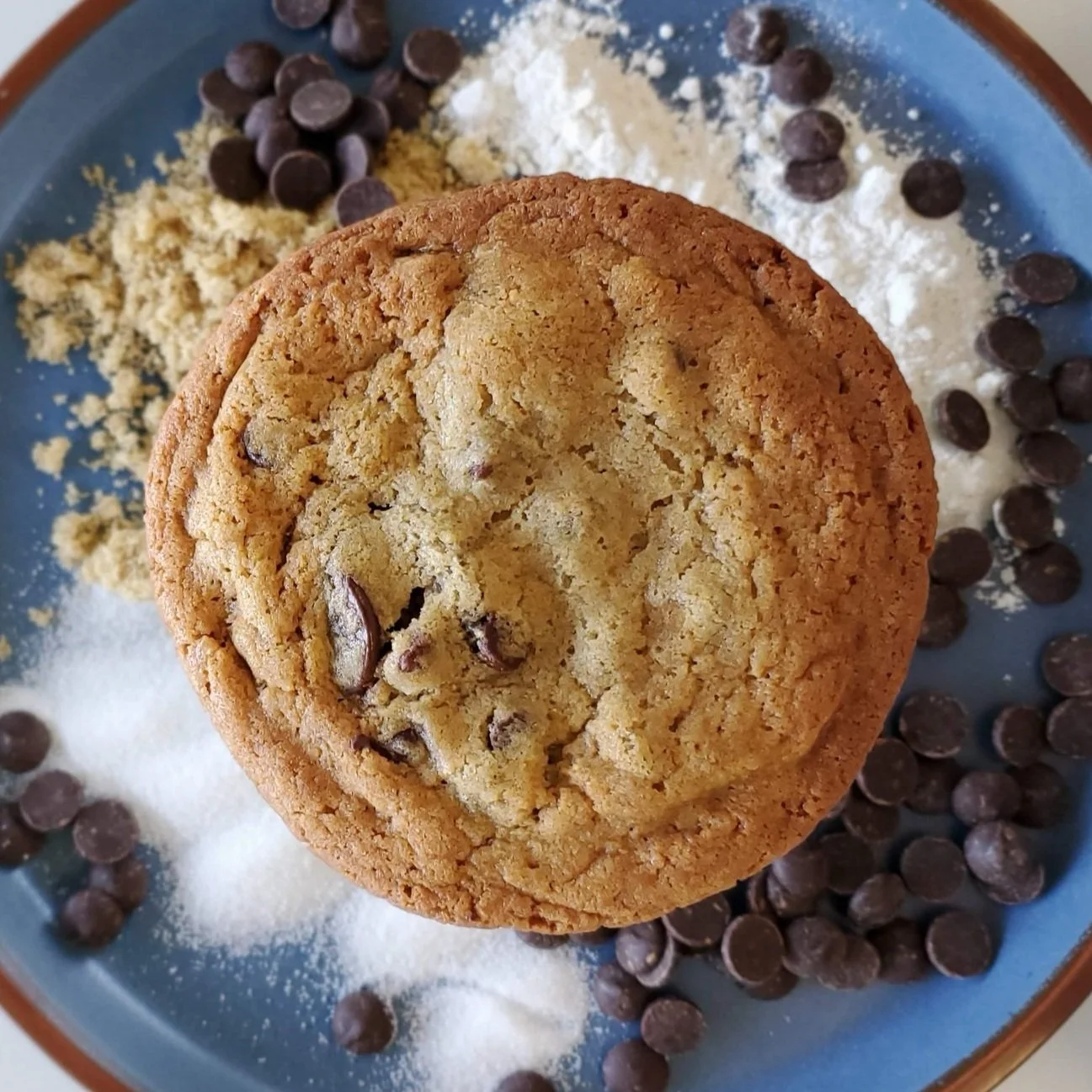 chocolate chip cookie with flour and sugar on blue background