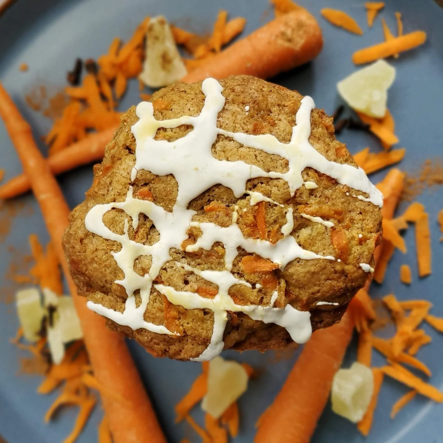 iced cookie with whole and shredded carrots, dried pineapple, and spices on a blue background