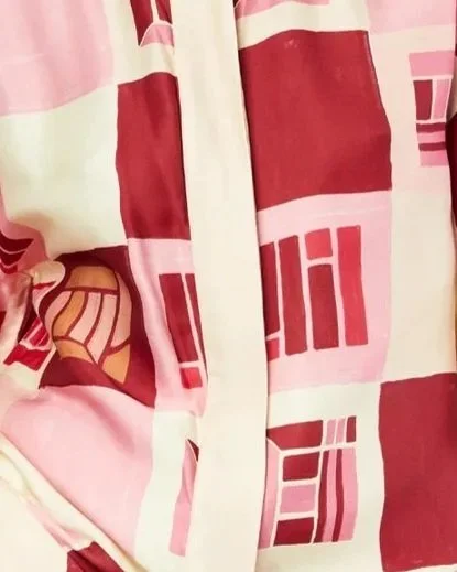 Close-up of a fabric with a red, pink, and cream geometric pattern and zipper.