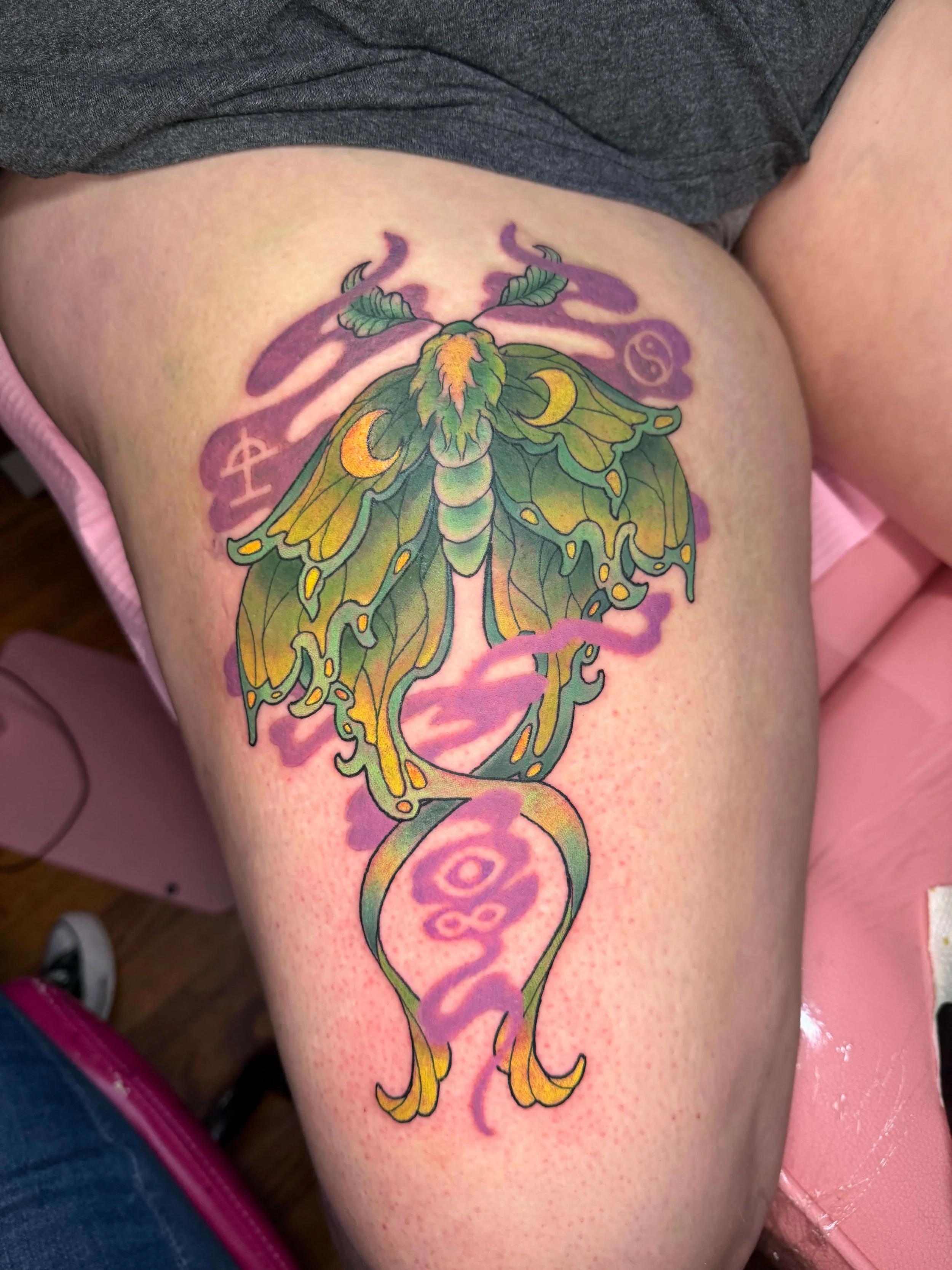 Luna moth thigh tattoo with purple smoke clouds by Erin Peterson at Integrity Tattoo in Denton Texas.