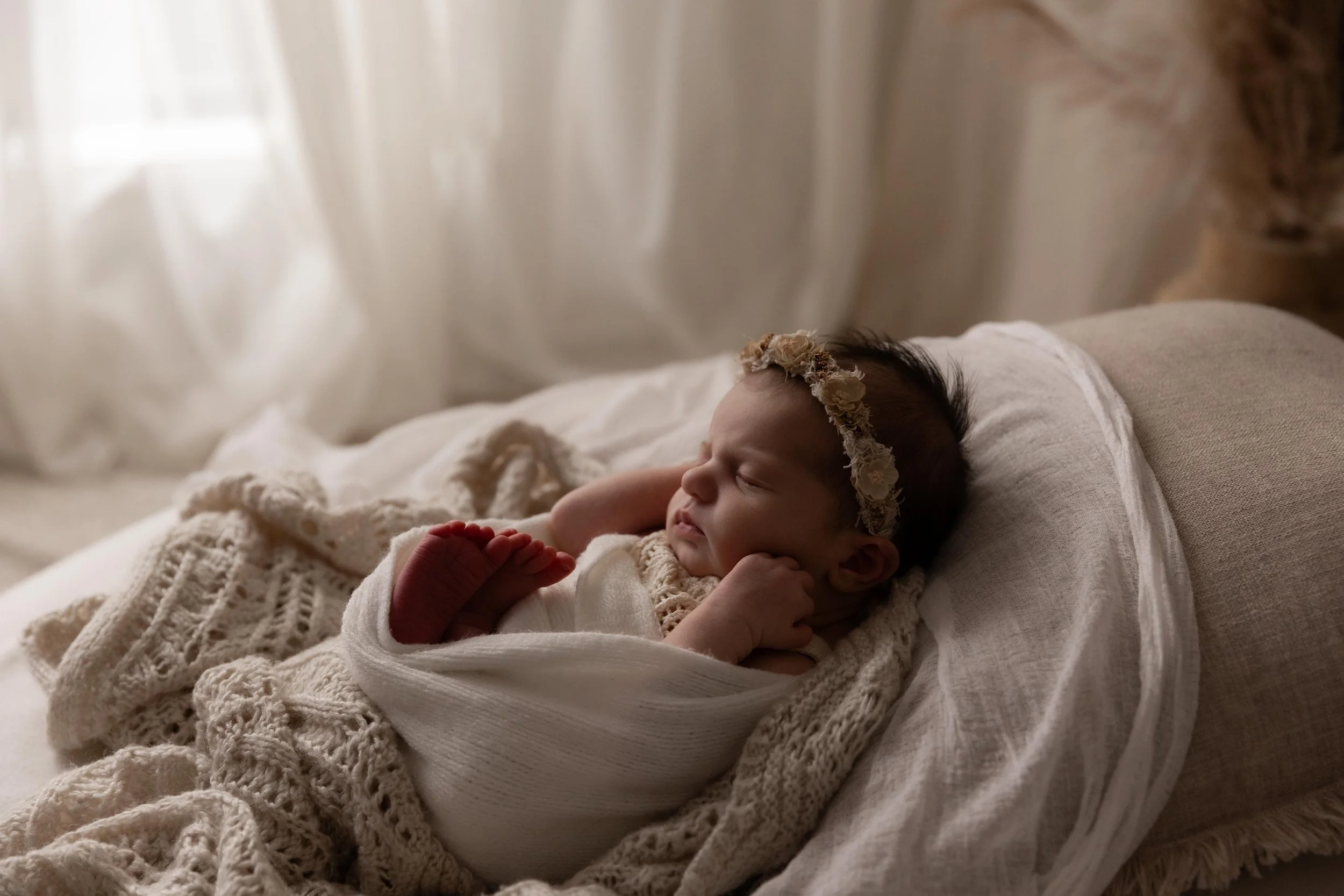 Peacefully sleeping newborn baby wrapped in soft, neutral tones during a newborn session in Doreen.
