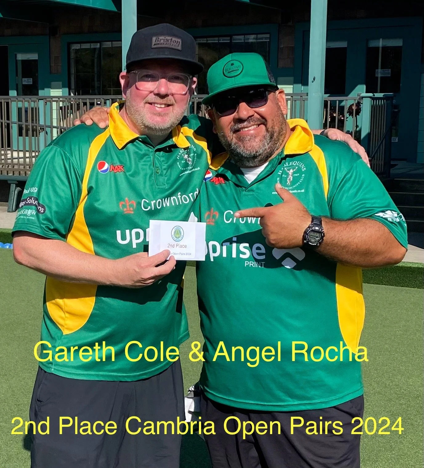 Two men in green and yellow sports shirts posing outdoors, one holding a second-place award card for Cambria Open Pairs 2024, with text overlay indicating their names Gareth Cole and Angel Rocha.