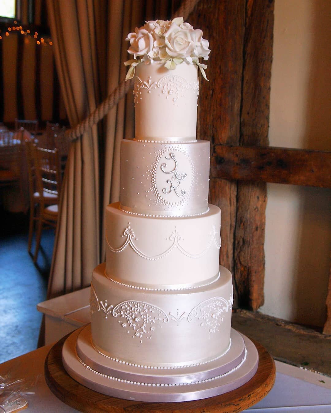 Intricate piped work for a cake I created a few years ago. The couple wanted only white with some silver and both the bride and groom loved my piped work. I created a design where their monogram was piped on one tier and two of the tiers were brushed