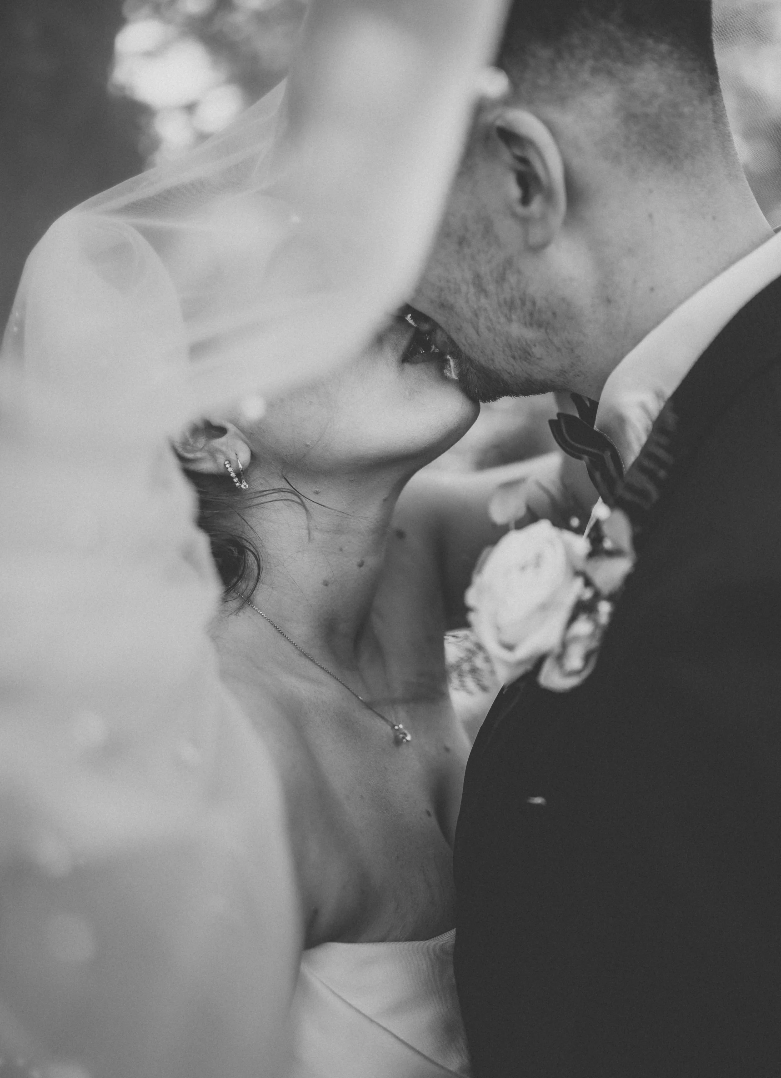 Black and white photo of a bride and groom close to each other, with their foreheads touching, sharing an intimate moment during their wedding.