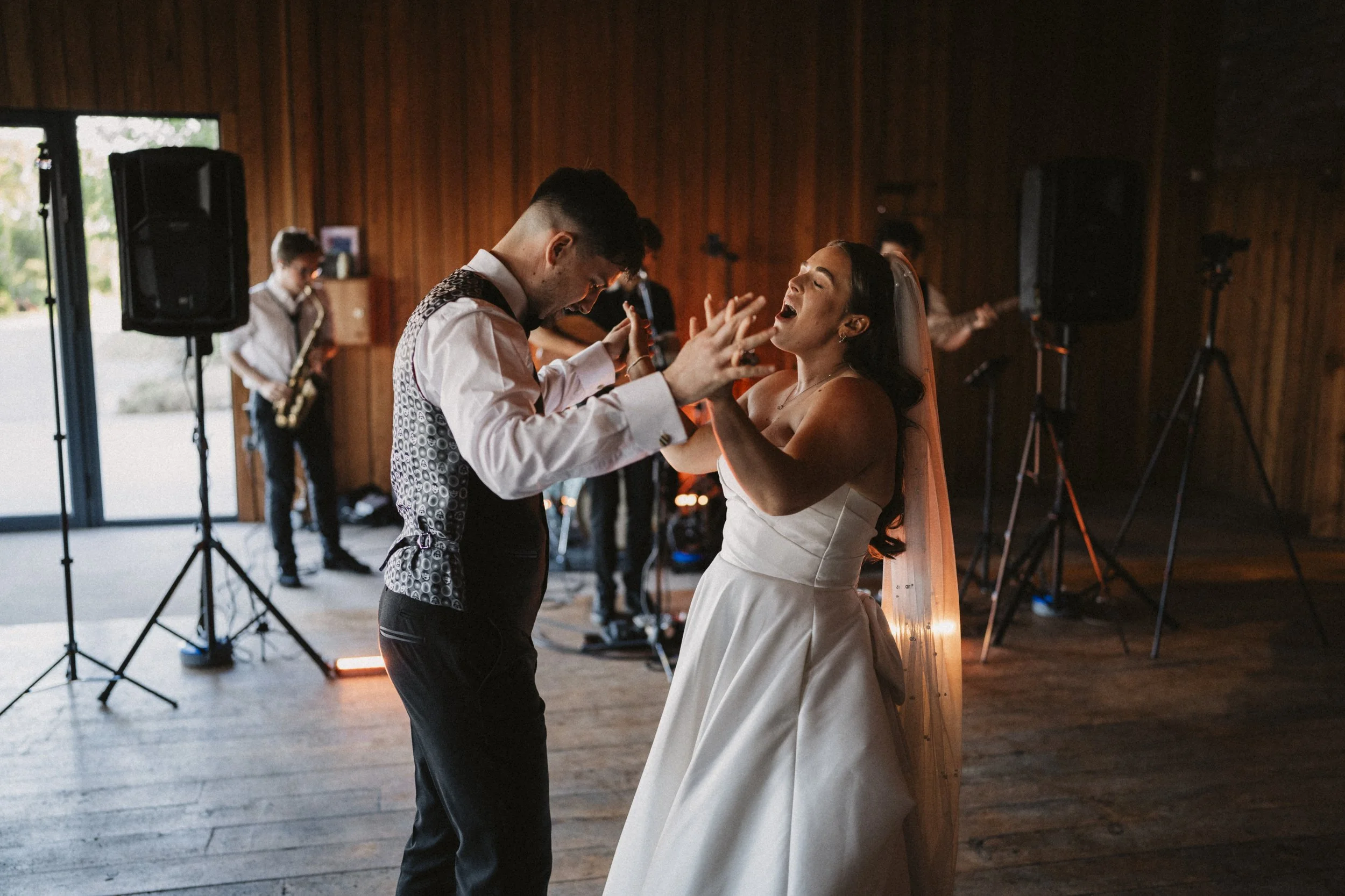 Bride and groom dancing at wedding reception with a band playing in the background.