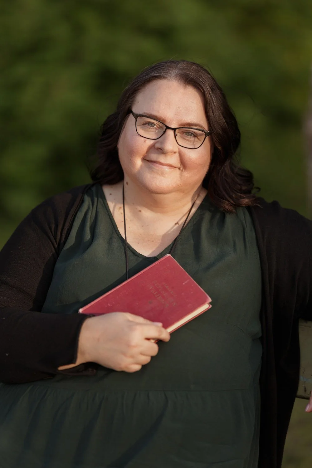 Spokesperson Annamari Typpö stands outside holding a red book.