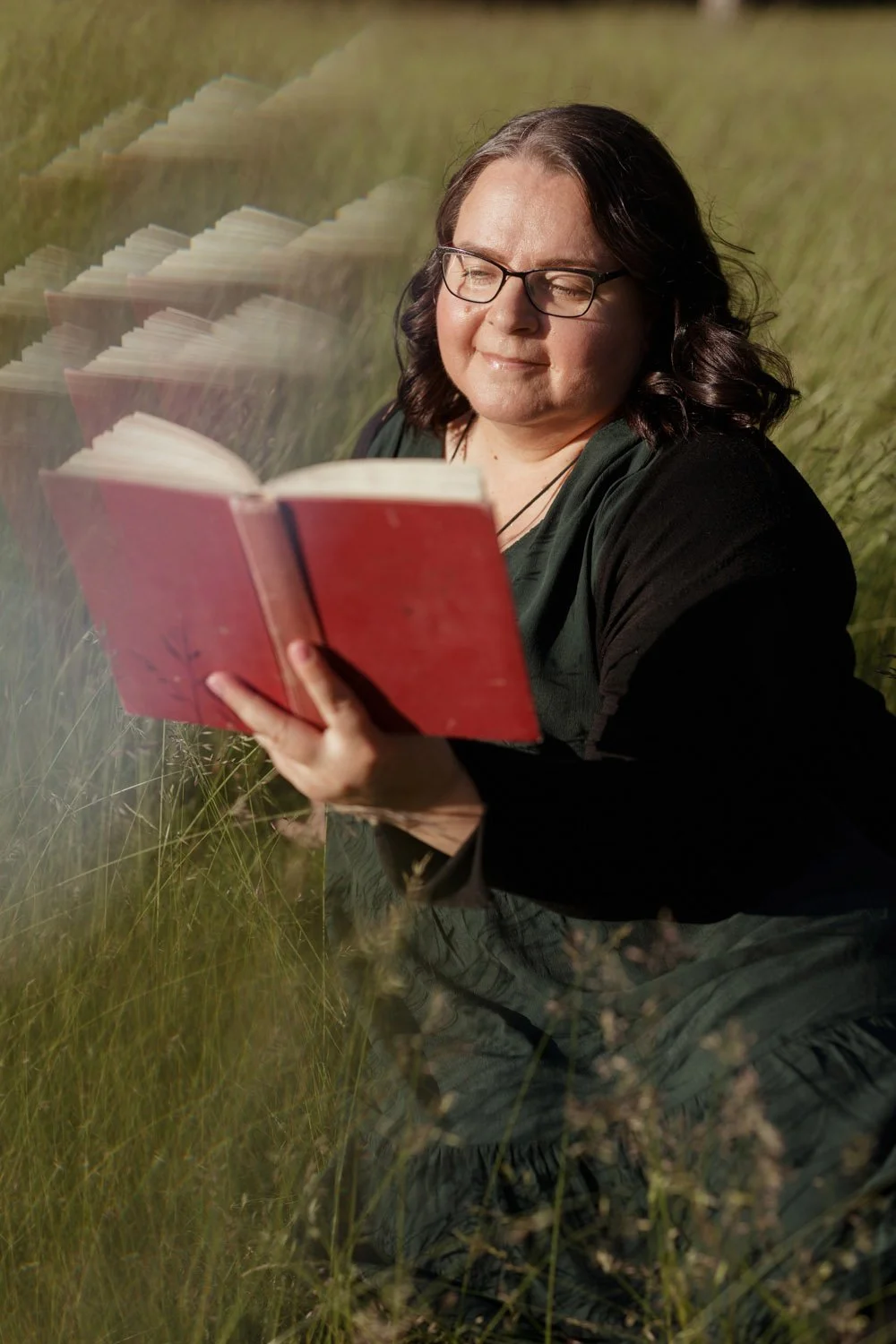 Spokesperson Annamari Typpö stands in a green meadow reading a red book.
