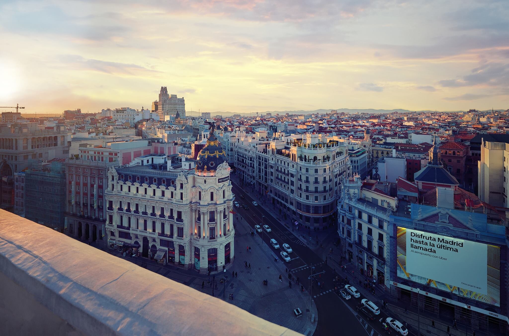 Aerial view of Madrid cityscape at sunset, showing historic buildings and busy streets.