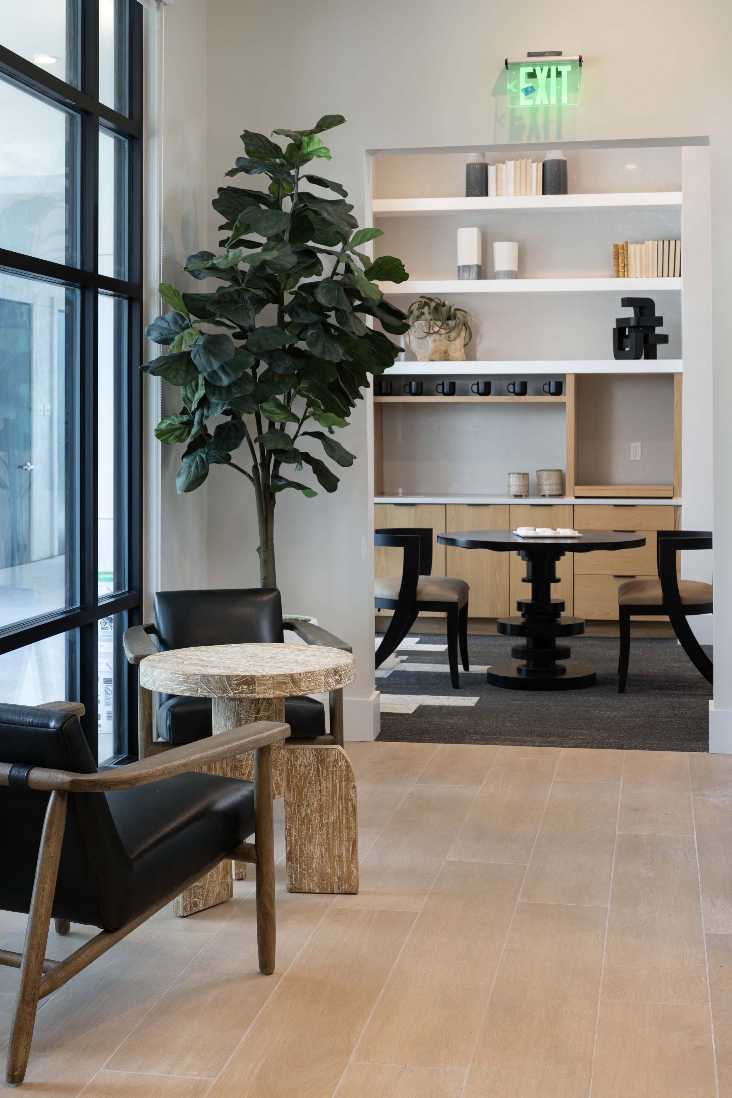 Interior of a modern cafe or office space with plants, wooden furniture, and decorative shelves.