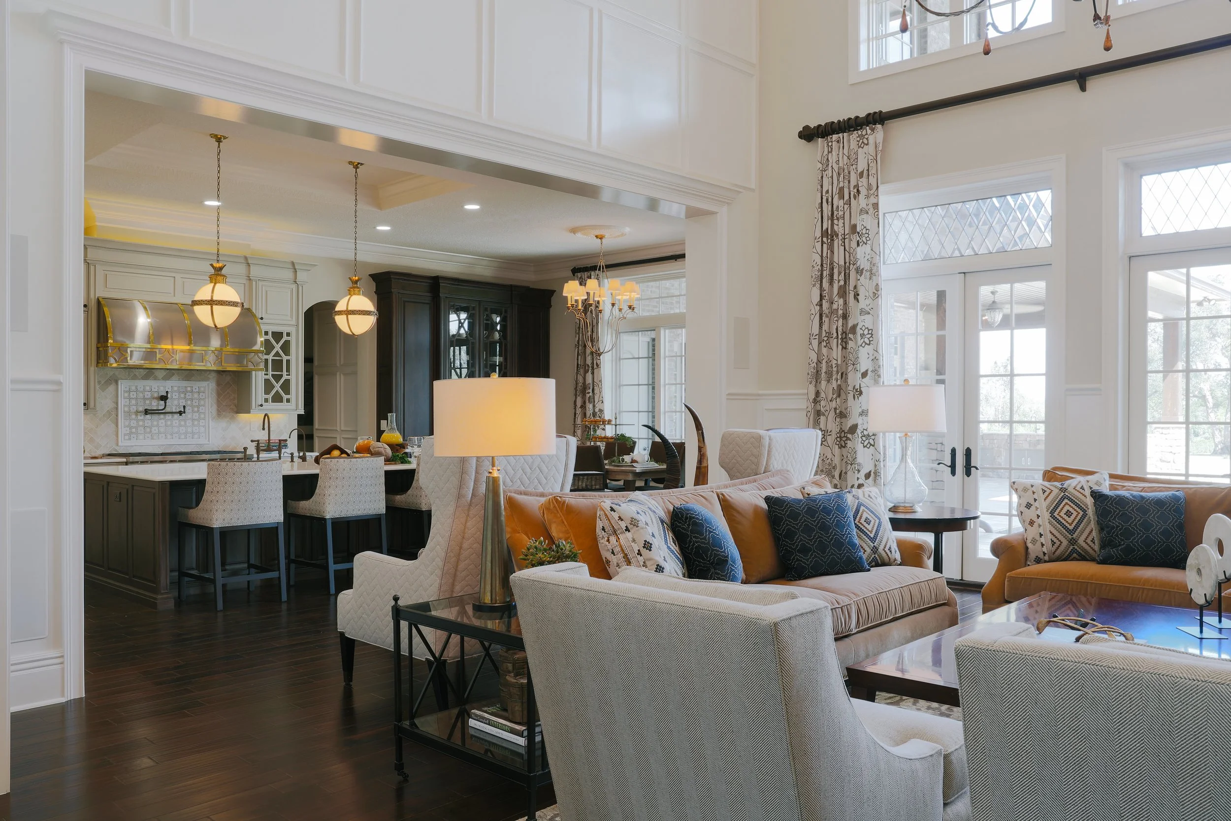 Open-concept living room and kitchen area with large windows, cozy seating, and elegant decor.