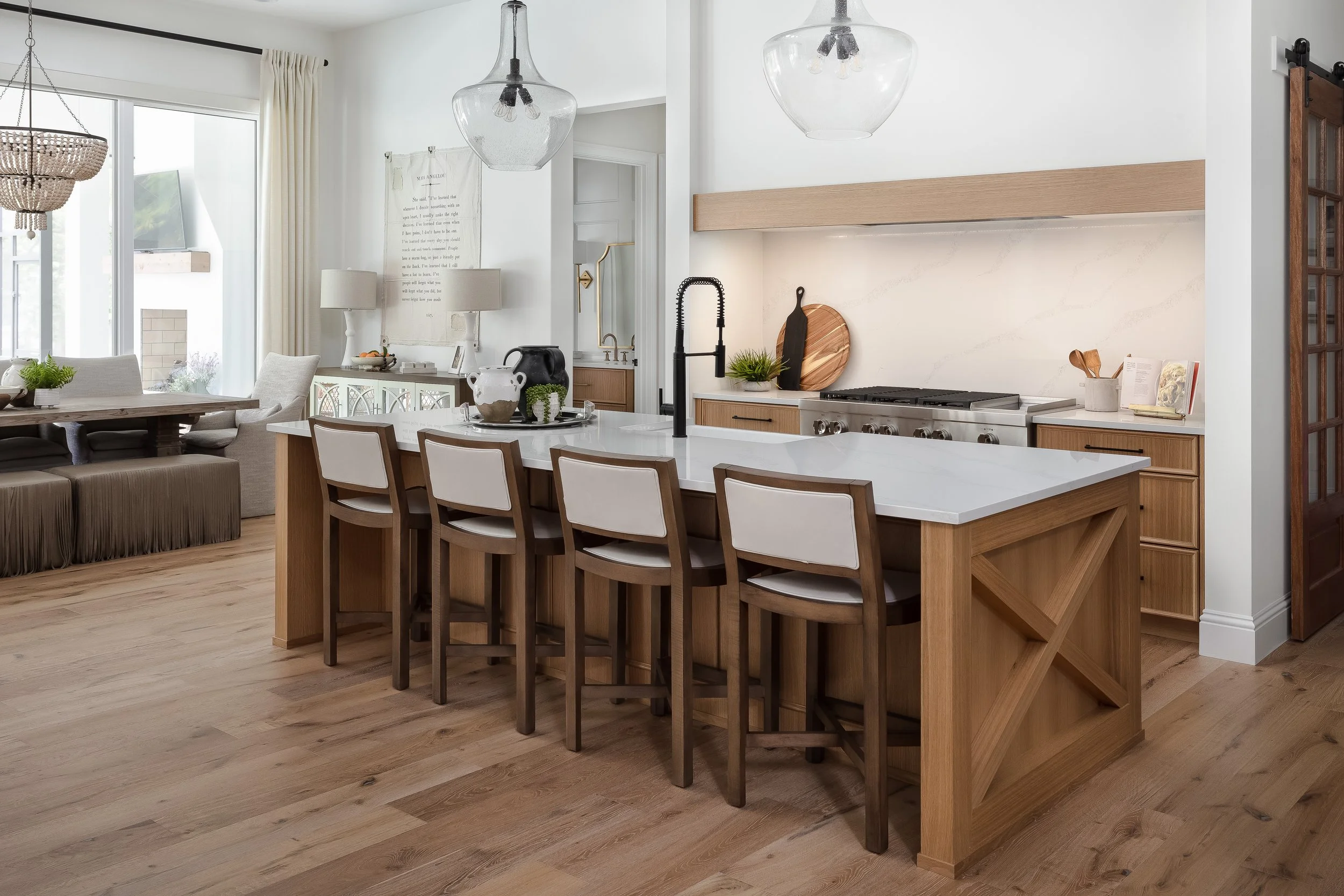 Open-concept kitchen and dining area with natural wood accents, white quartz countertops, pendant lighting, and a mix of modern and rustic decor.
