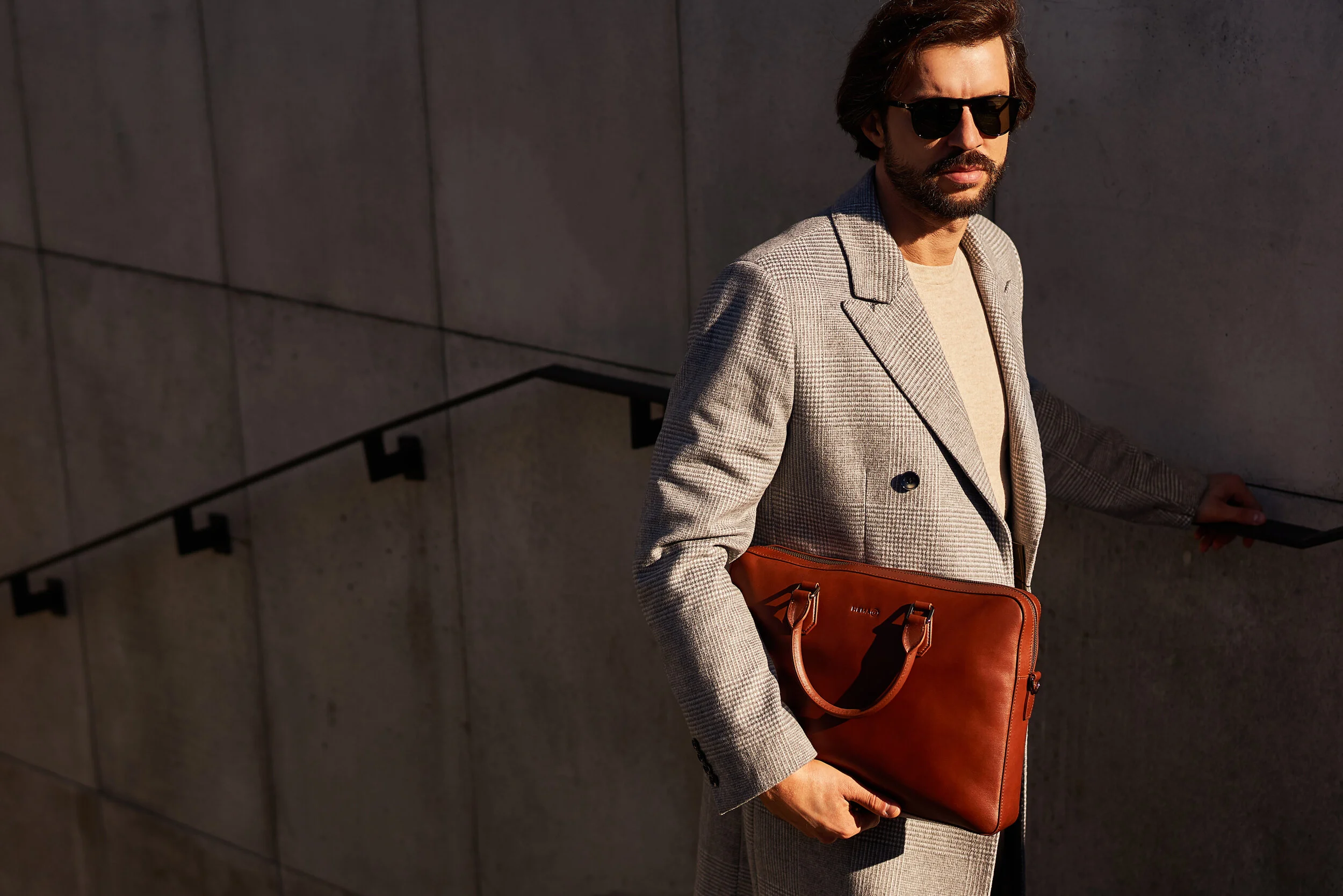 Mężczyzna trzyma neseser. Fotografia Fashion.